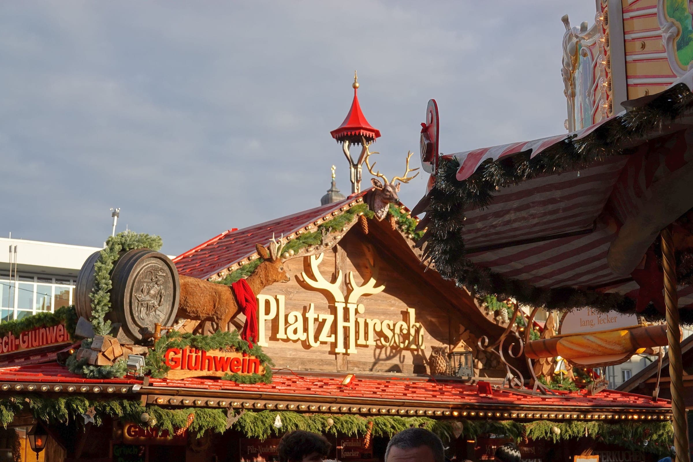 A carved stag and a red Glühwein sign crown a stall roof at Dresden's Striezelmarkt