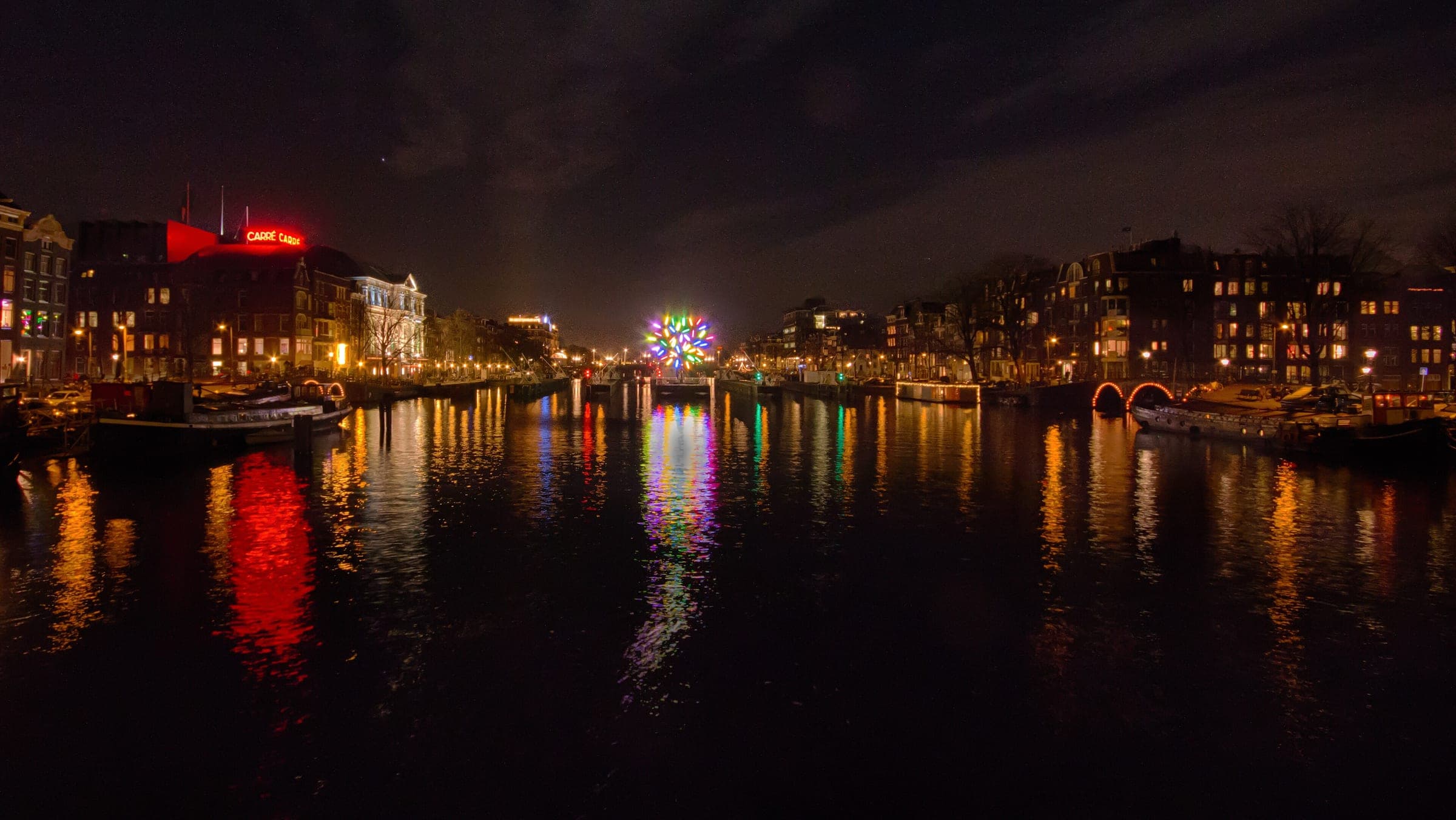 Carré Theatre and the lights of Amsterdam Light Festival shine across the Amstel on a January night.