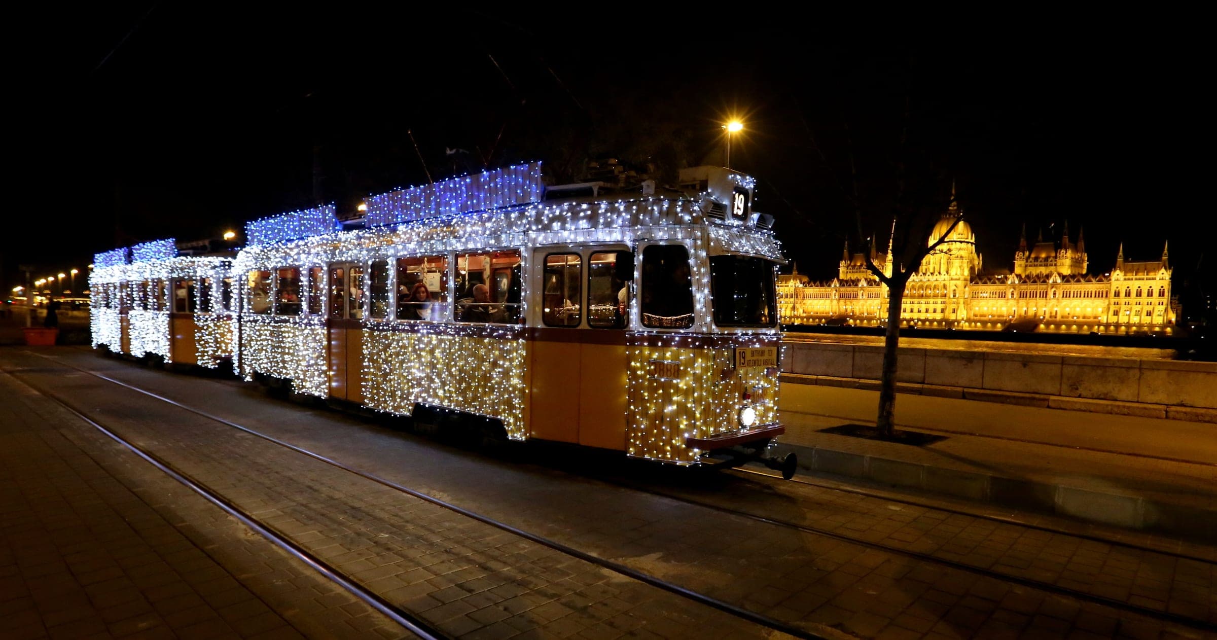 The Light Tram runs along the Danube embankment in Budapest with the floodlit Parliament across the river.
