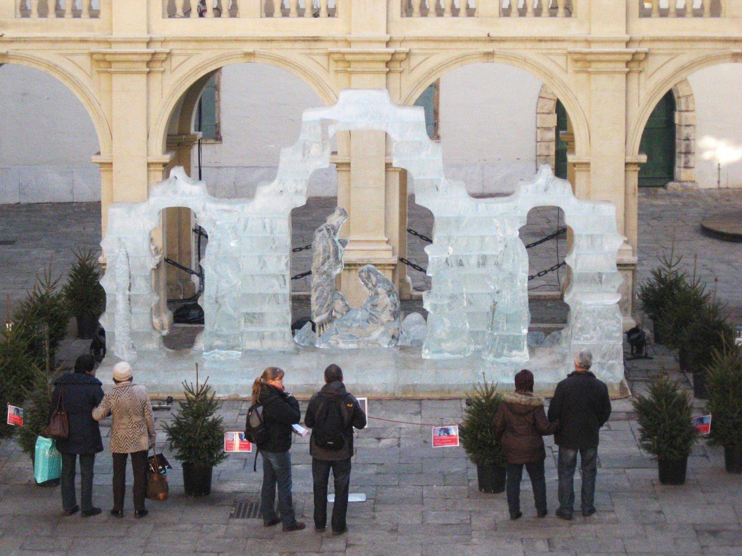 Visitors stand among potted firs in the Landhaushof in Graz to look at the ice nativity in December.