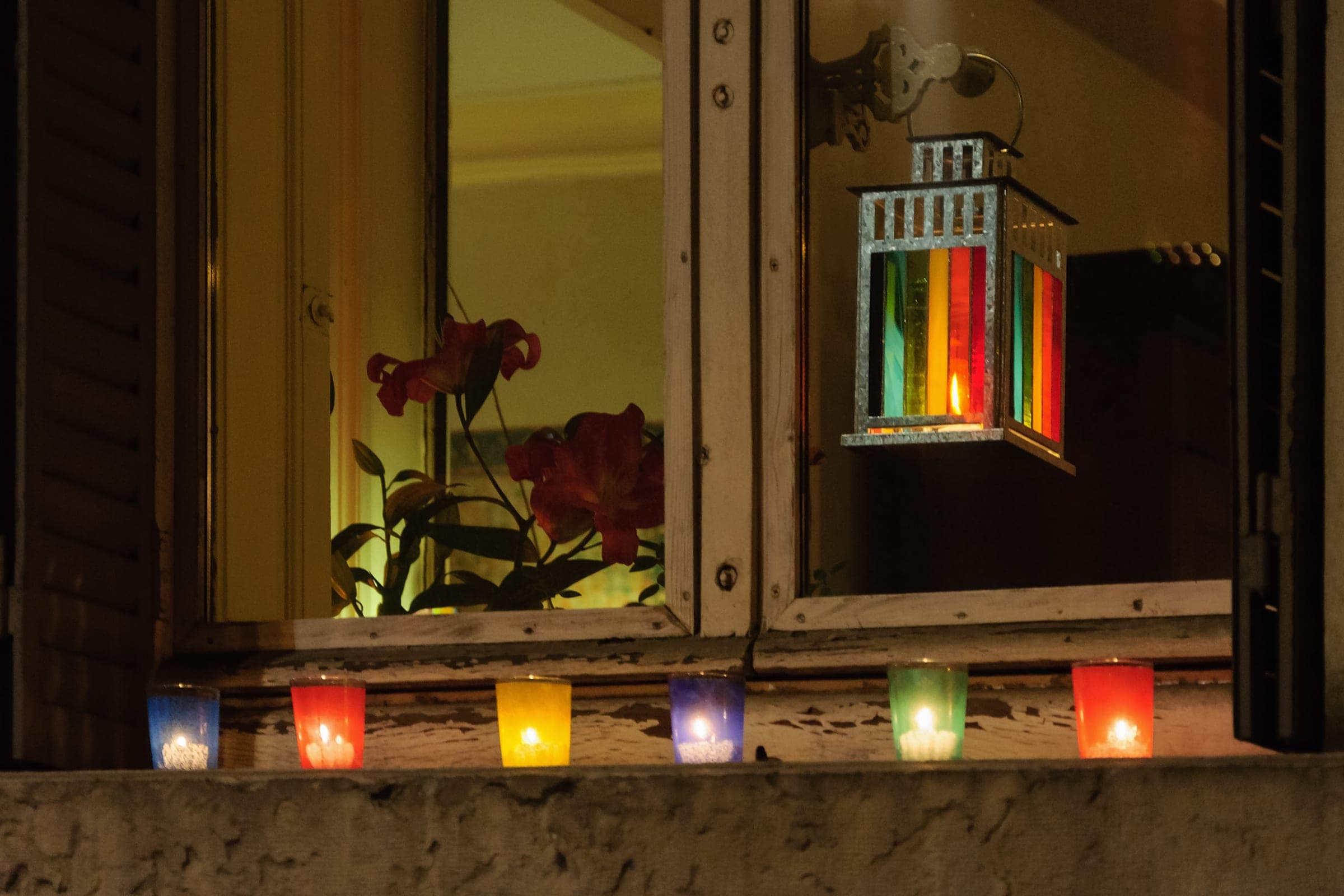 Coloured lumignons burn on a Lyon window ledge on 8 December below a lantern of stained glass.