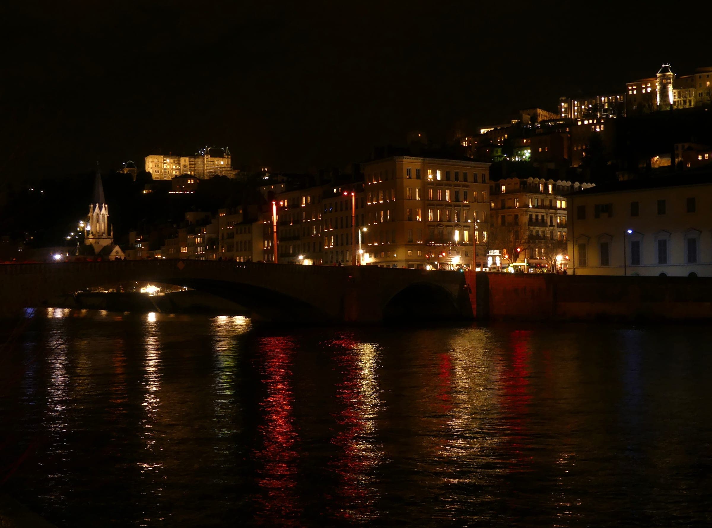 Lit windows on the right bank of the Saône climb toward Fourvière on the evening of 8 December in Lyon.