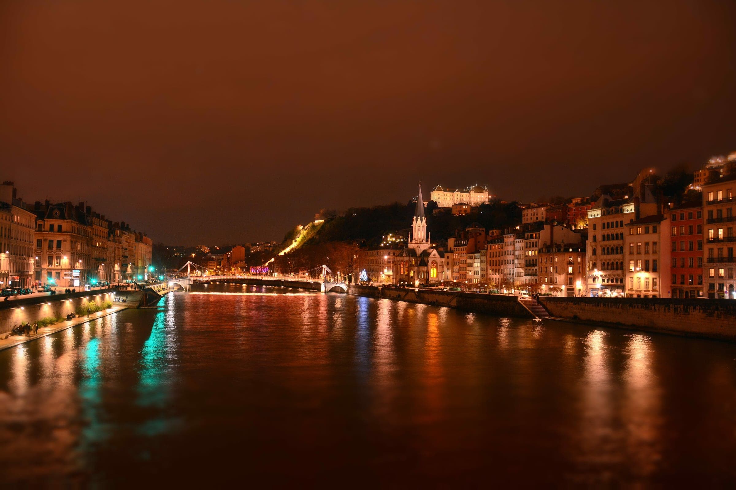 Lights from the Saône quays and the Fourvière hill shimmer on the river during the Fête des Lumières in Lyon.