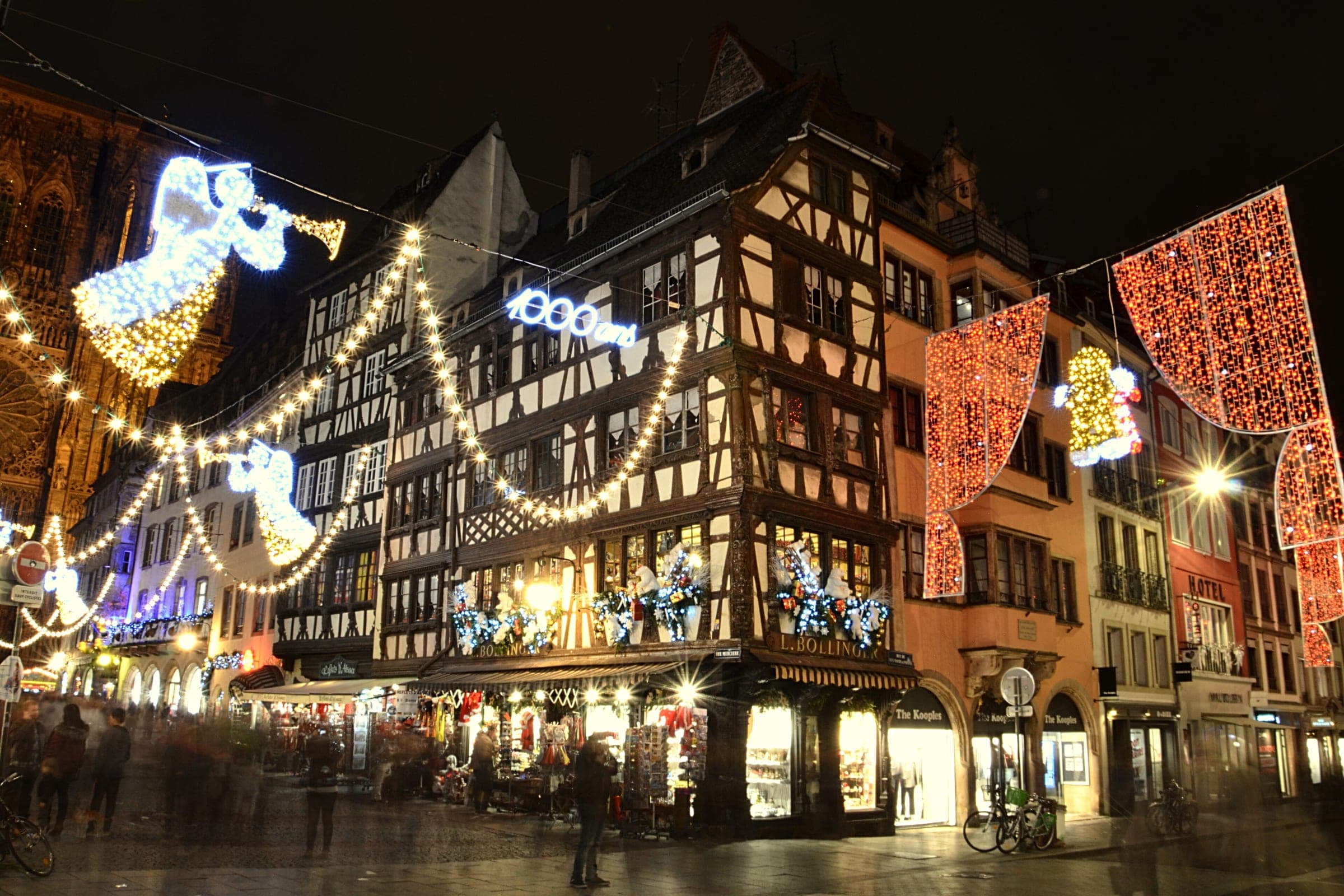 Garlands and a lit angel hang over the half-timbered houses near Strasbourg Cathedral on a December night.