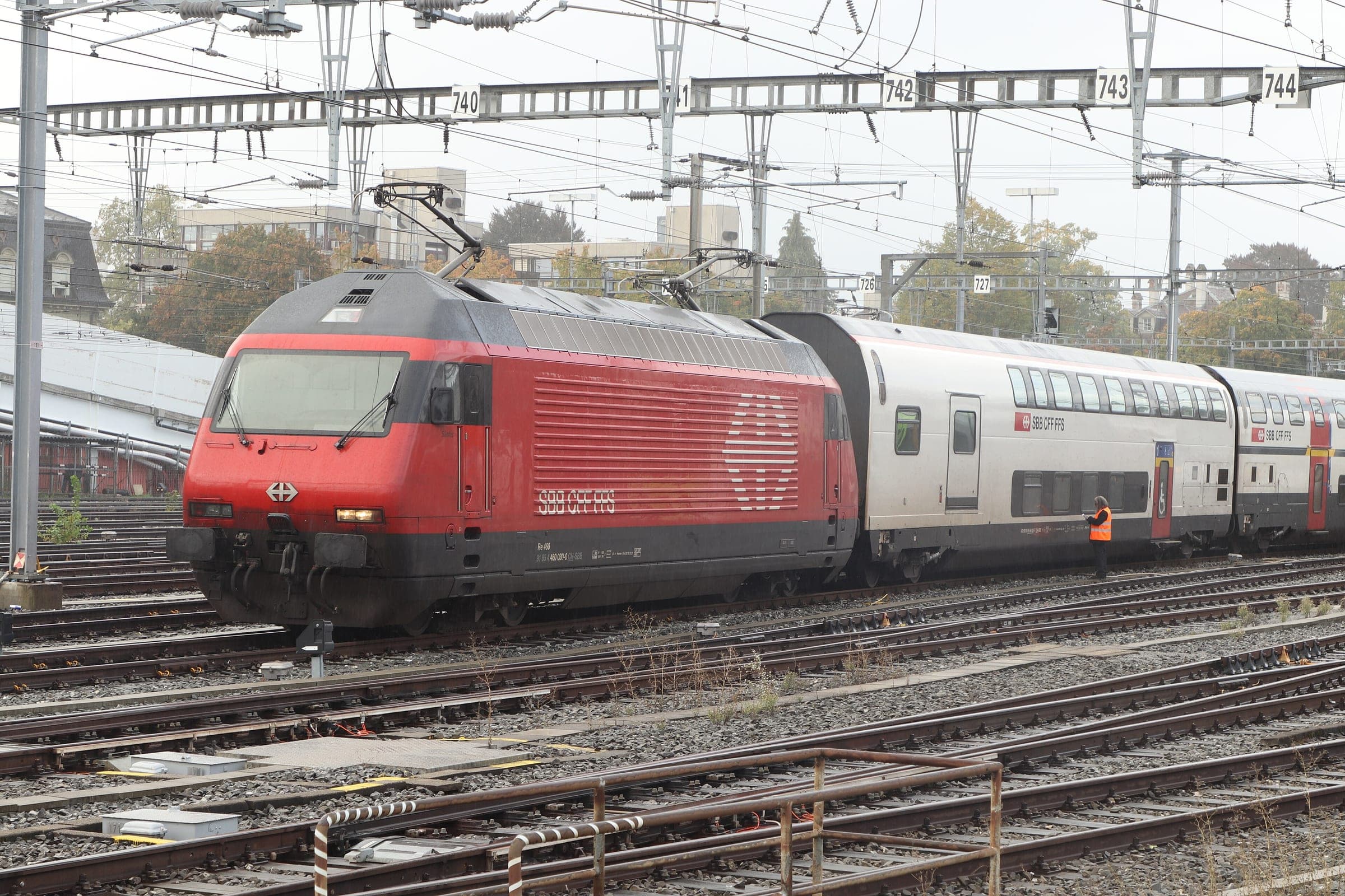 An SBB Re 460 locomotive with IC2000 double-deck coaches waits outside Bern station.
