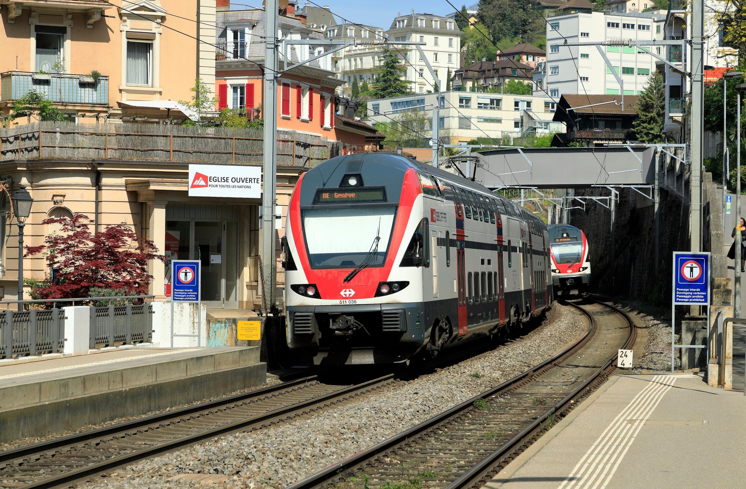 An SBB RegioExpress double-deck train stops at Montreux station below the town's apartment blocks.