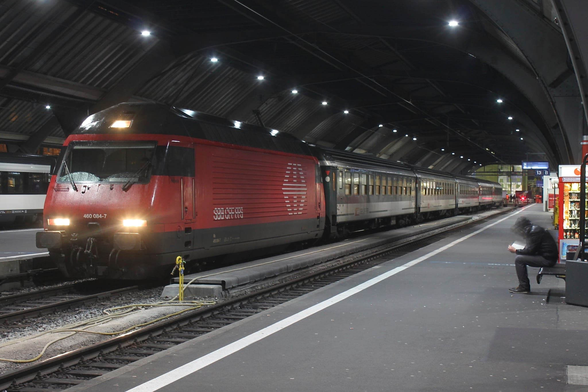 An SBB Re 460 heads an InterRegio to Basel at night under the platform roof of Zürich HB.
