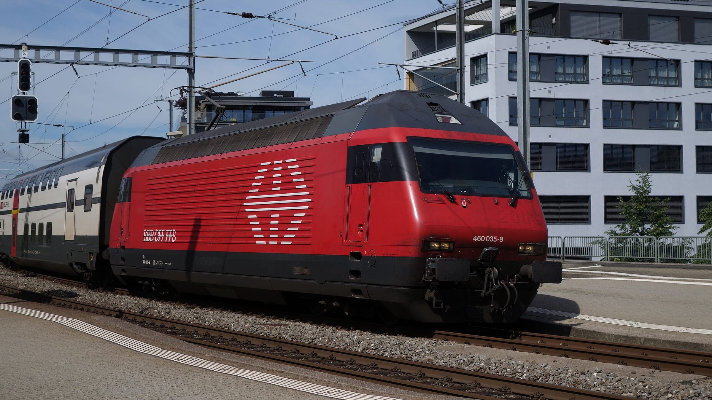 An SBB Re 460 hauls an InterRegio between Lucerne and Zürich through Zug station.