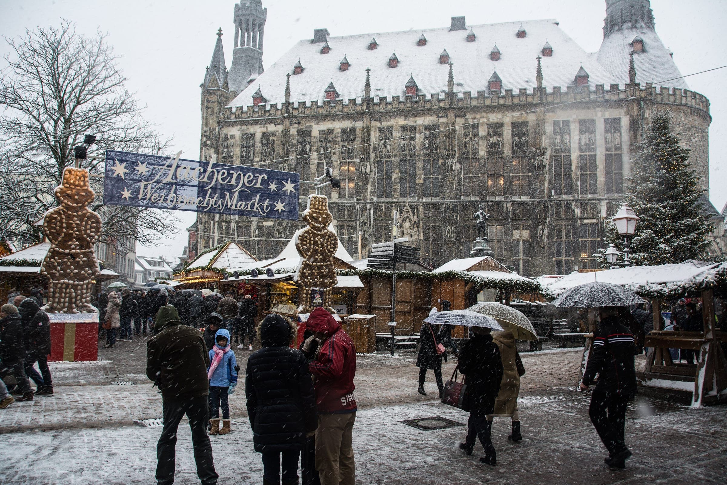 Snow falls on the Aachen Christmas market entrance with its gingerbread men below the town hall