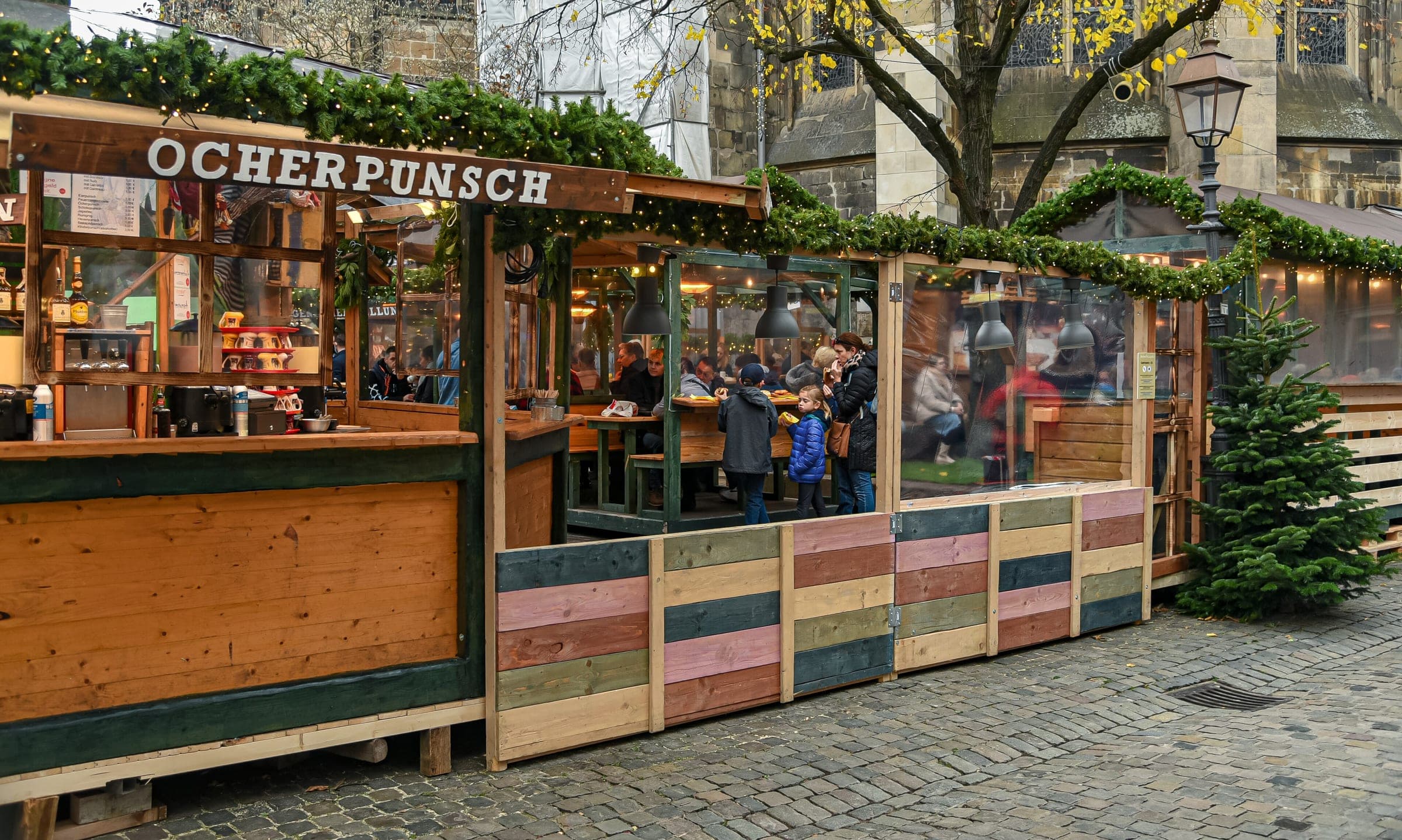 Visitors drink punch inside the wooden Öcherpunsch stall at the Aachen Christmas market