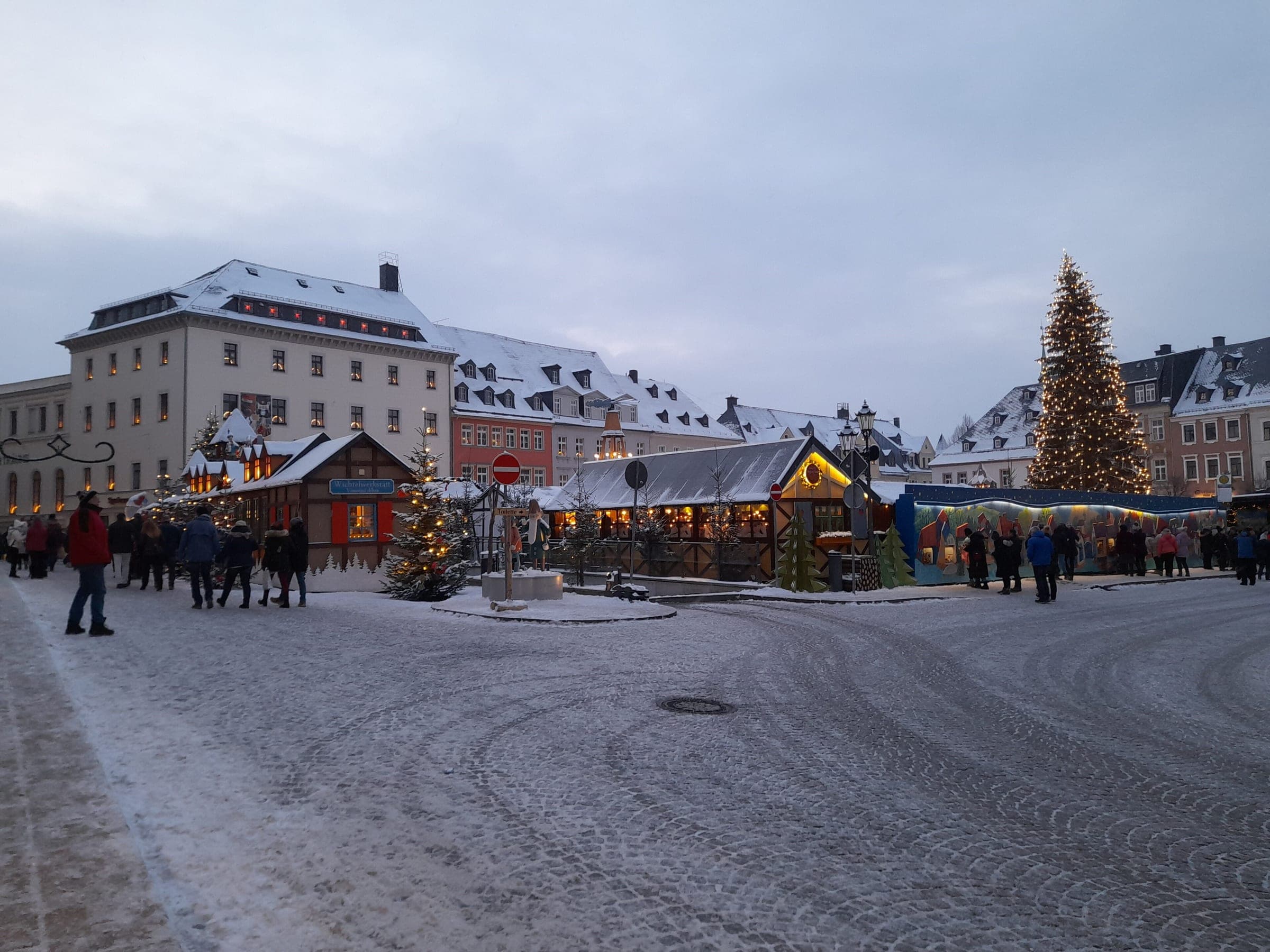 Snow lies on the Markt in Annaberg-Buchholz around its stalls and tall Christmas tree.