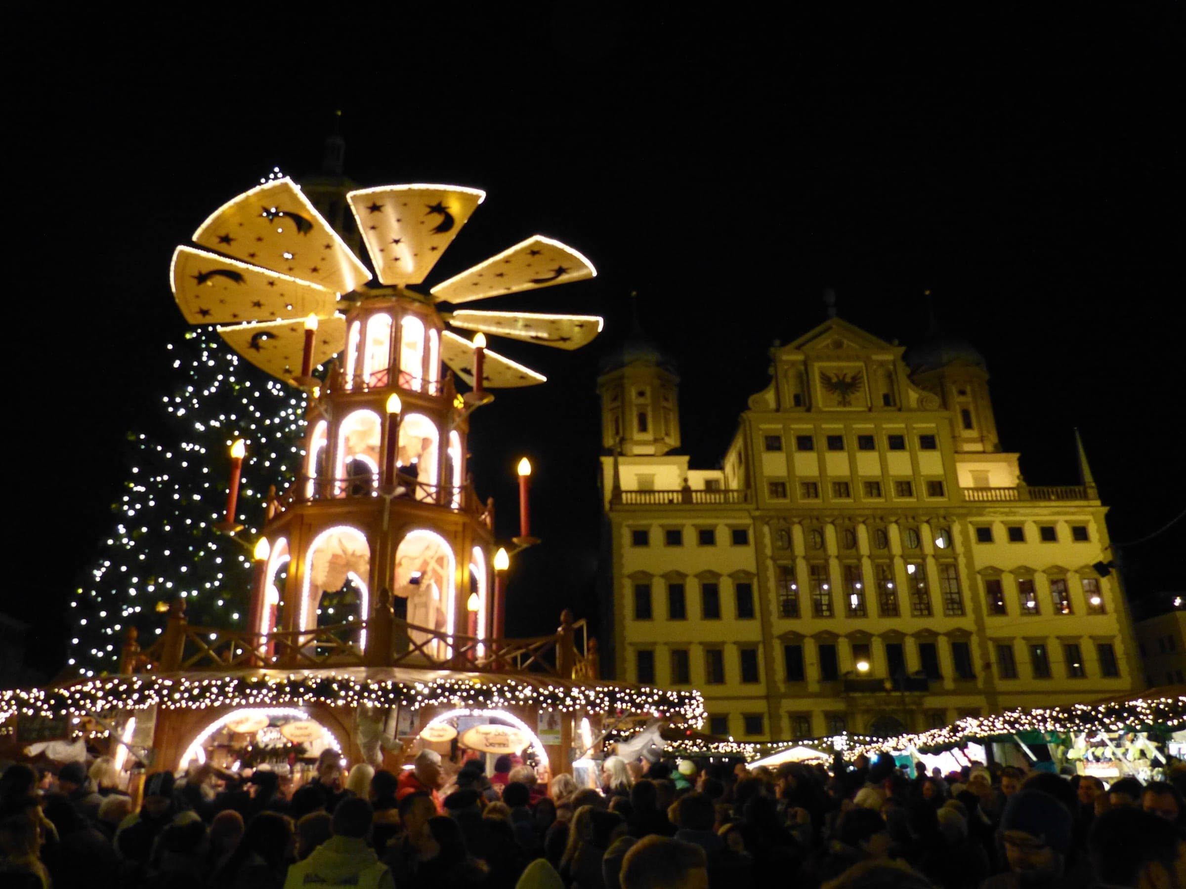 The candle pyramid and Christmas tree glow at night in front of Augsburg's Renaissance town hall.