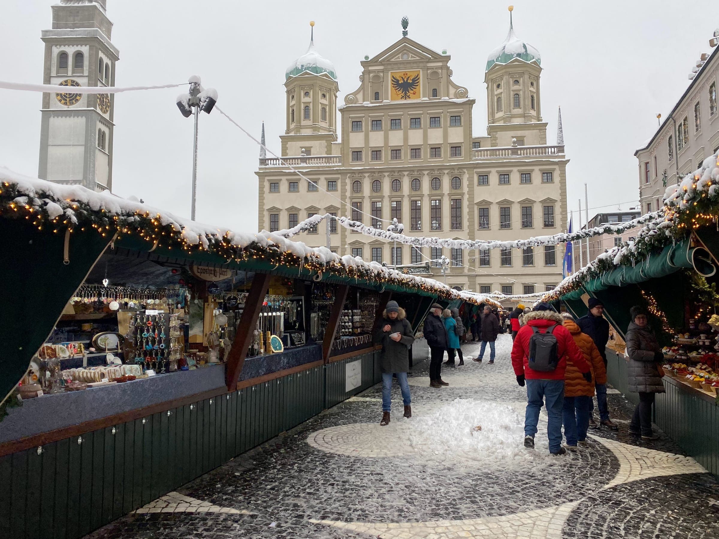 Snow covers the stall roofs on Rathausplatz in Augsburg with the town hall and Perlach Tower behind.