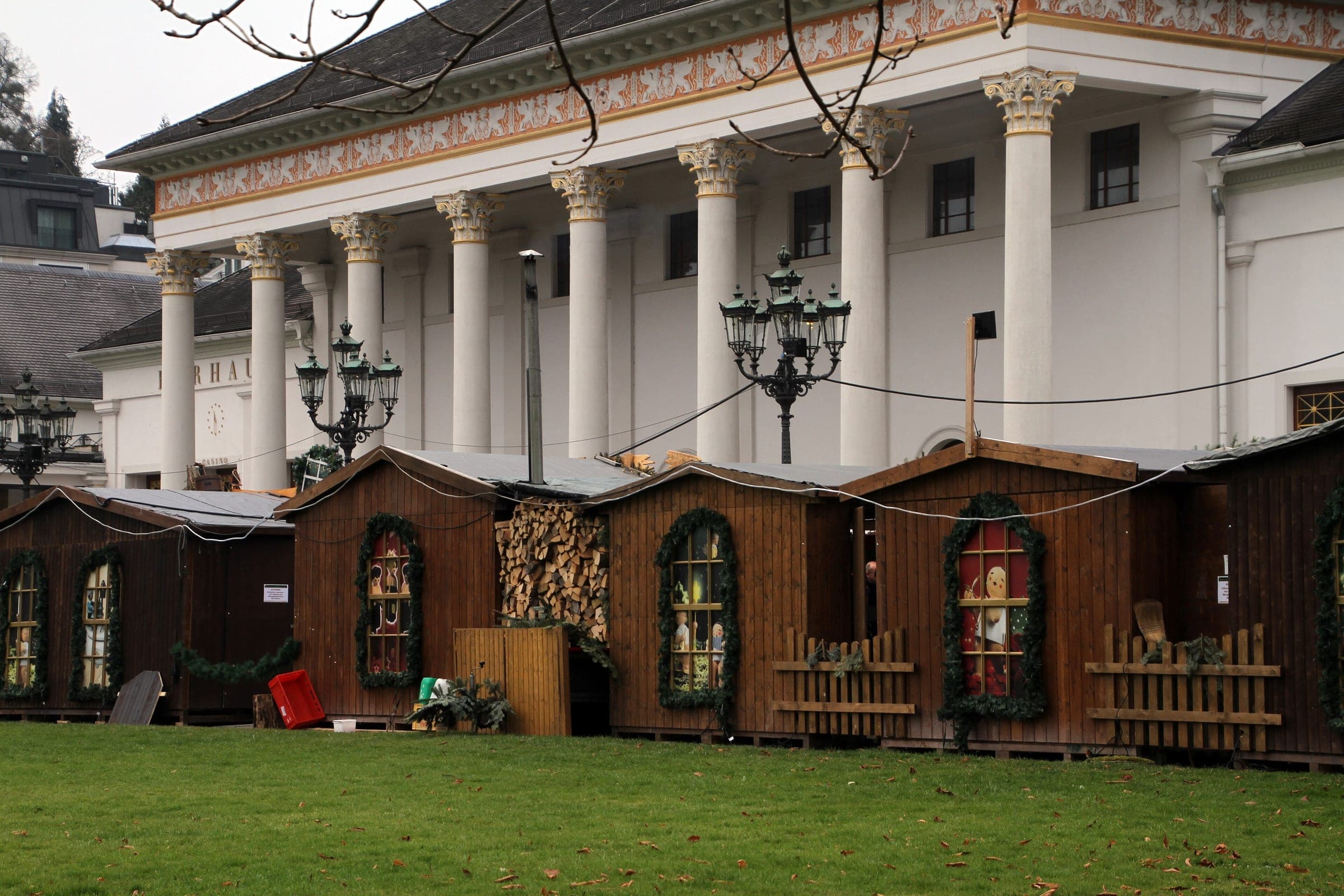 Wooden market huts stand on the lawn in front of the white columns of the Kurhaus in Baden-Baden.