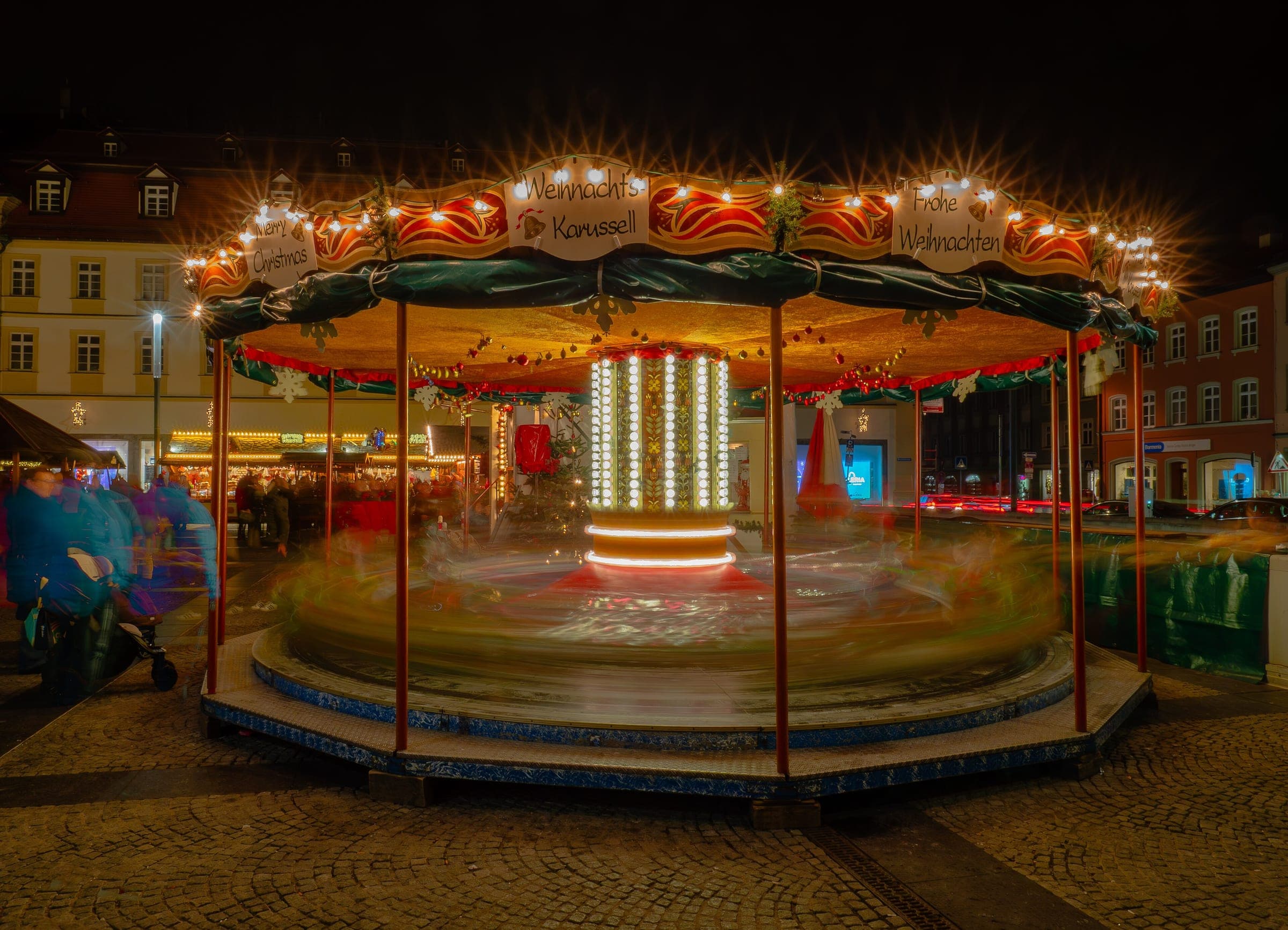 A carousel spins in a blur of lights at the Bamberg Christmas market at night