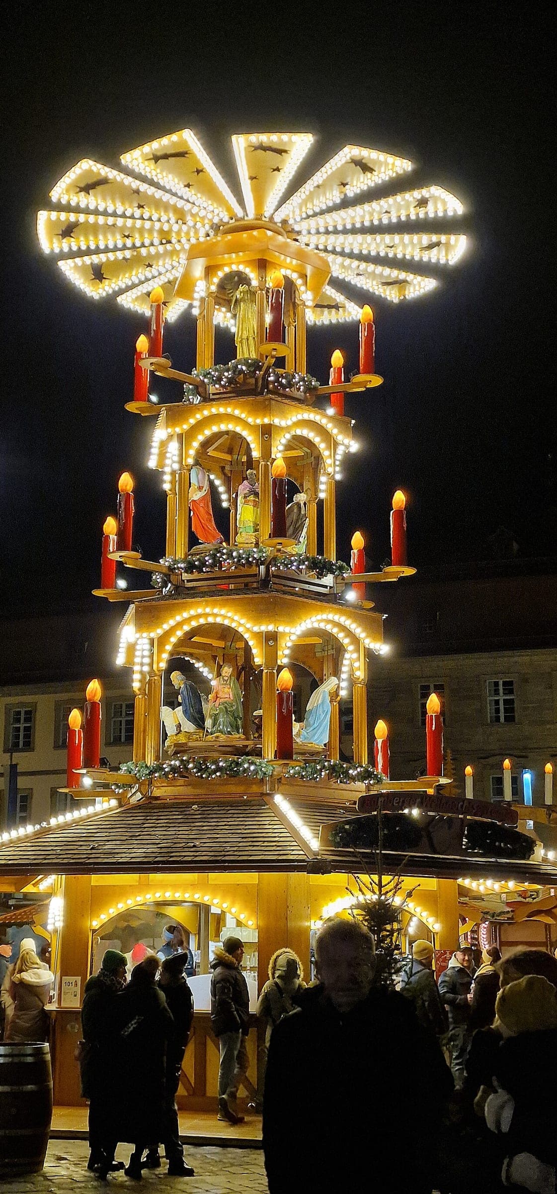 A Christmas pyramid with candles and carved figures turns at the Bamberg Christmas market at night