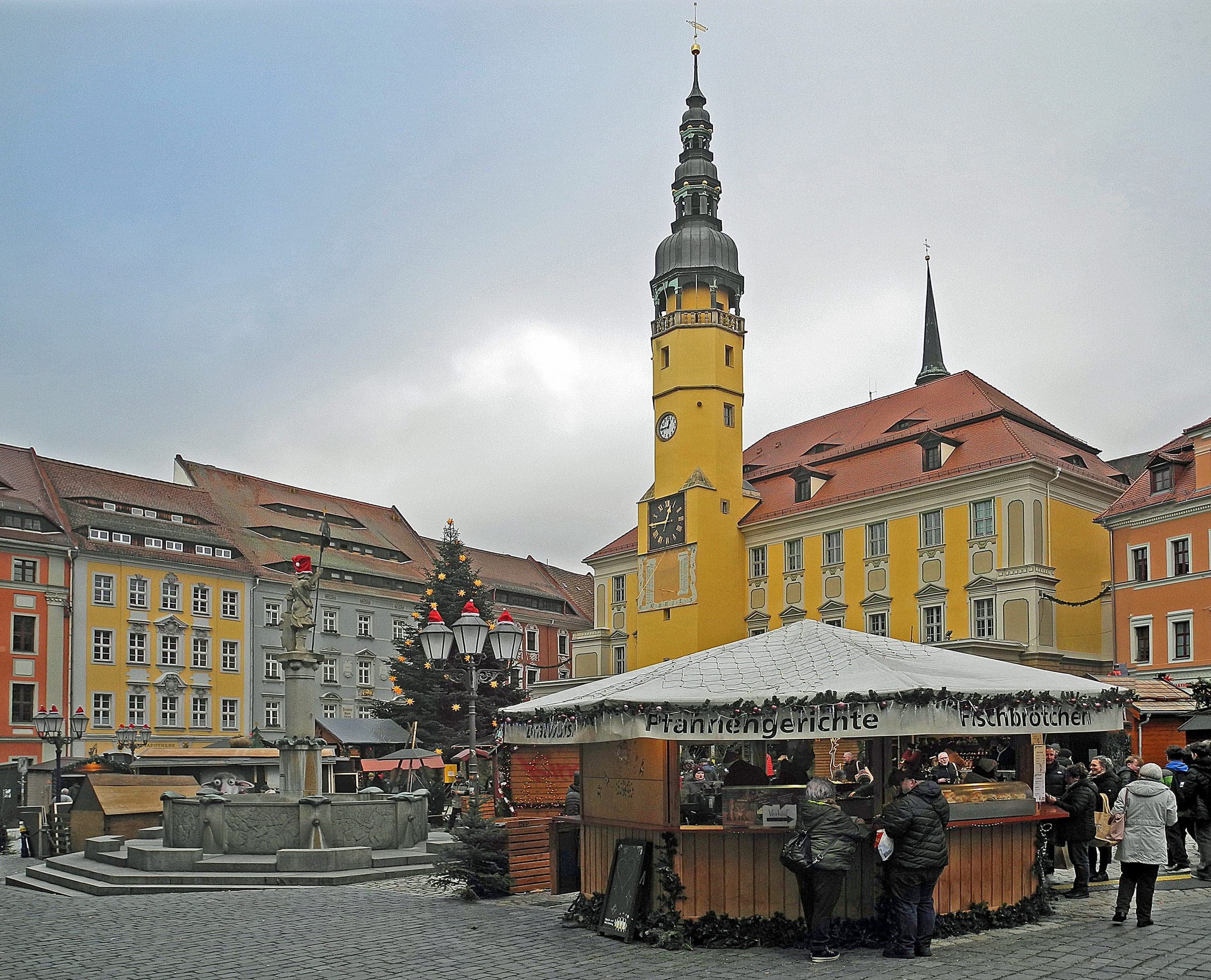 Stalls of the Wenzelsmarkt stand on Bautzen's Hauptmarkt below the yellow tower of the town hall.