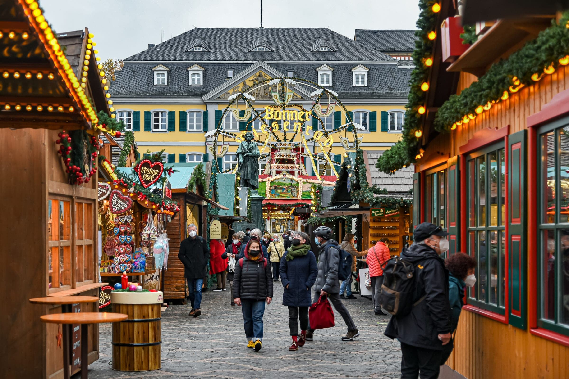 Shoppers walk a lane of lit huts towards the Beethoven statue at the Bonn Christmas market