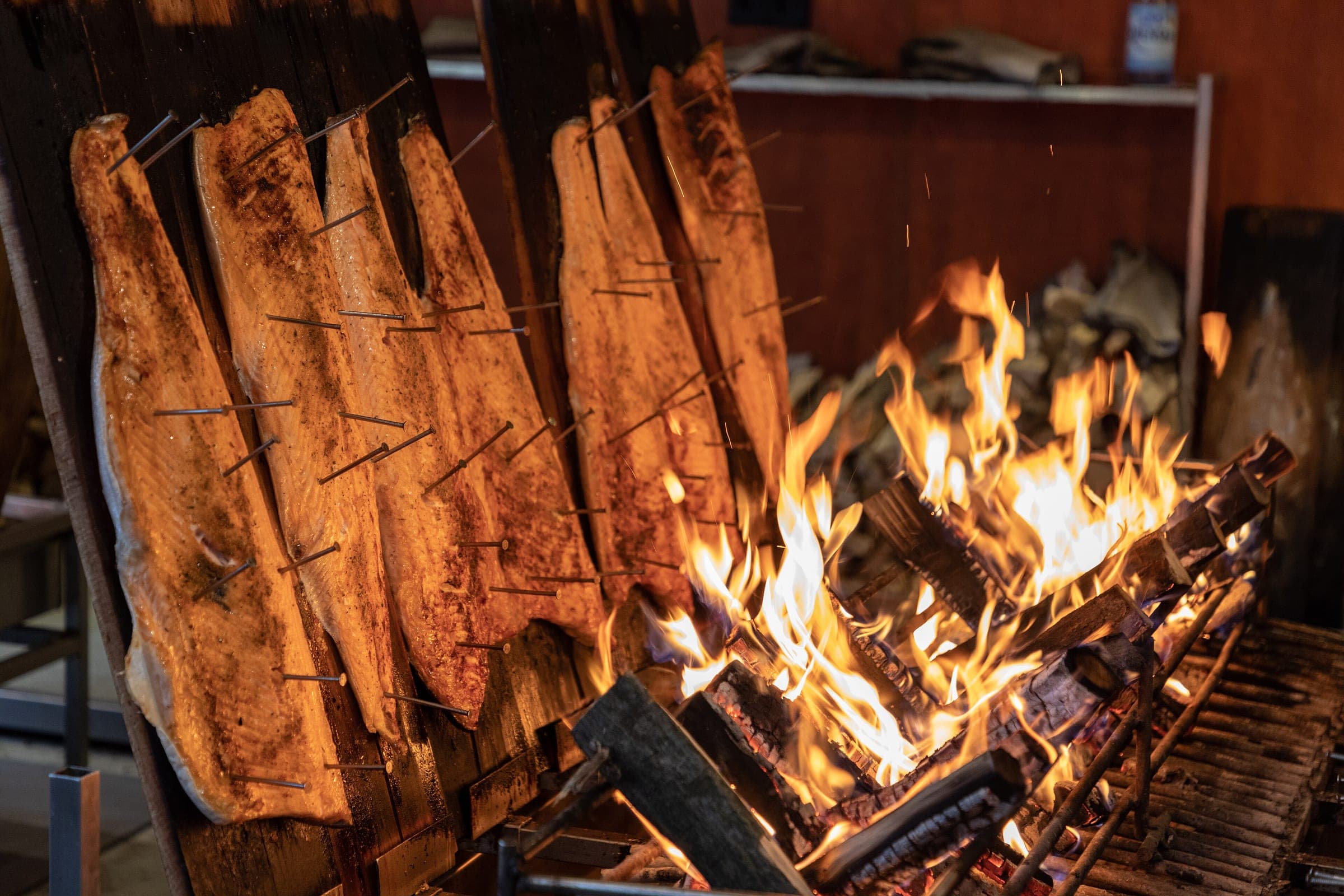 Salmon fillets nailed to wooden boards roast beside an open fire at the Bonn Christmas market