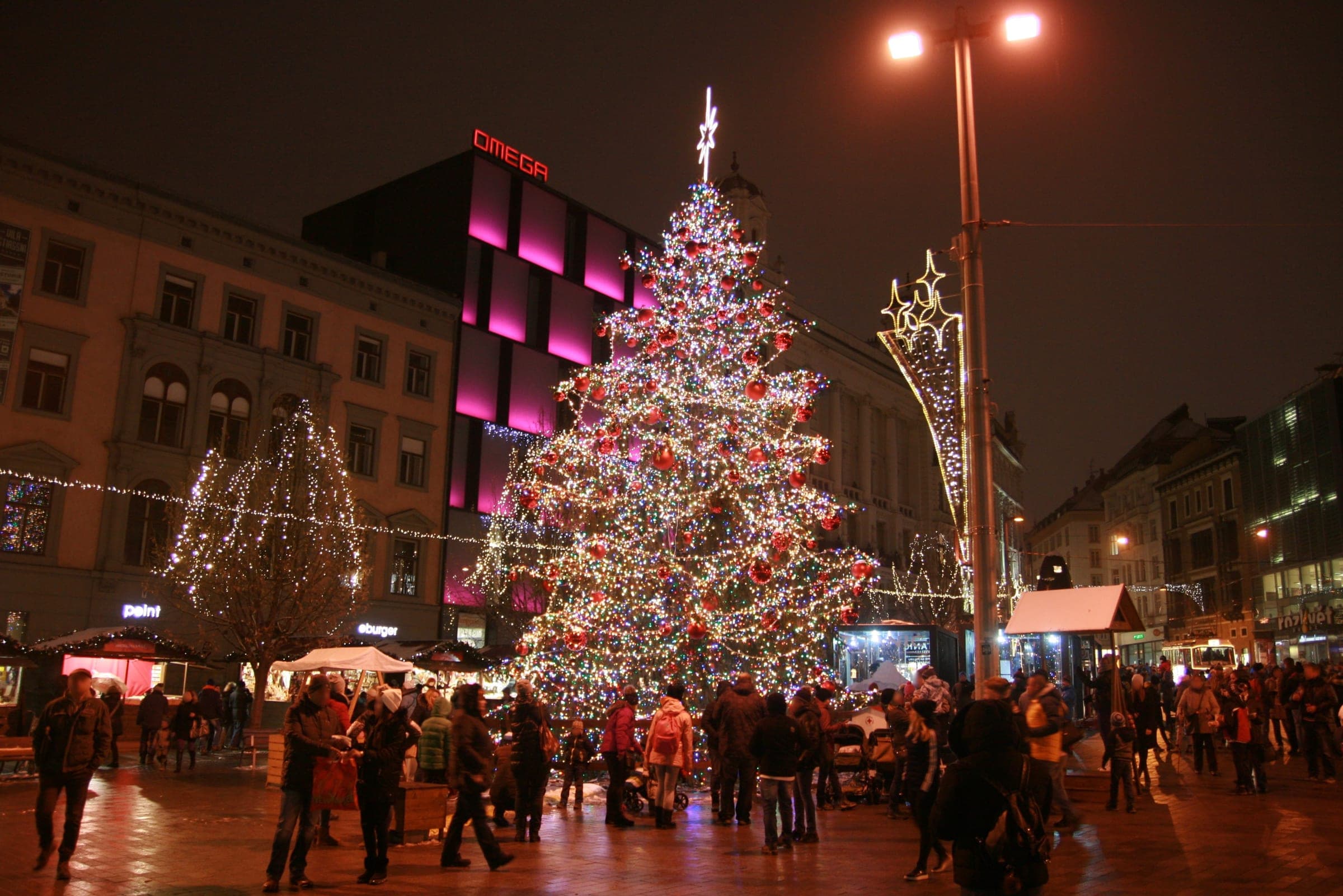 A tall Christmas tree lit in red and gold rises over the market stalls on náměstí Svobody in Brno.