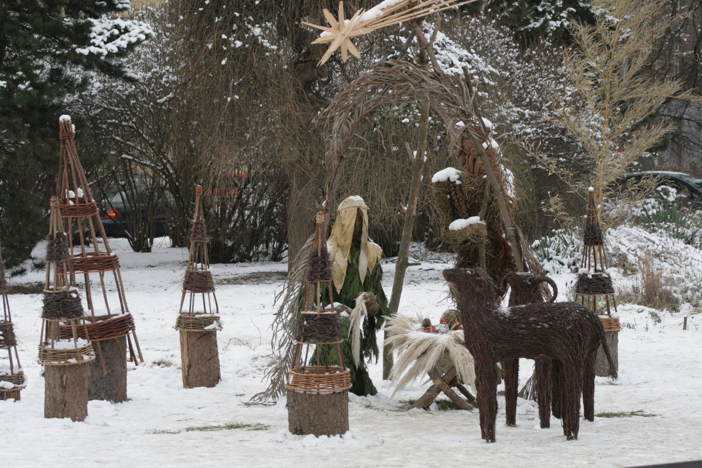 Wicker and straw nativity figures stand in the snow on Moravské náměstí during the Brno Christmas market.