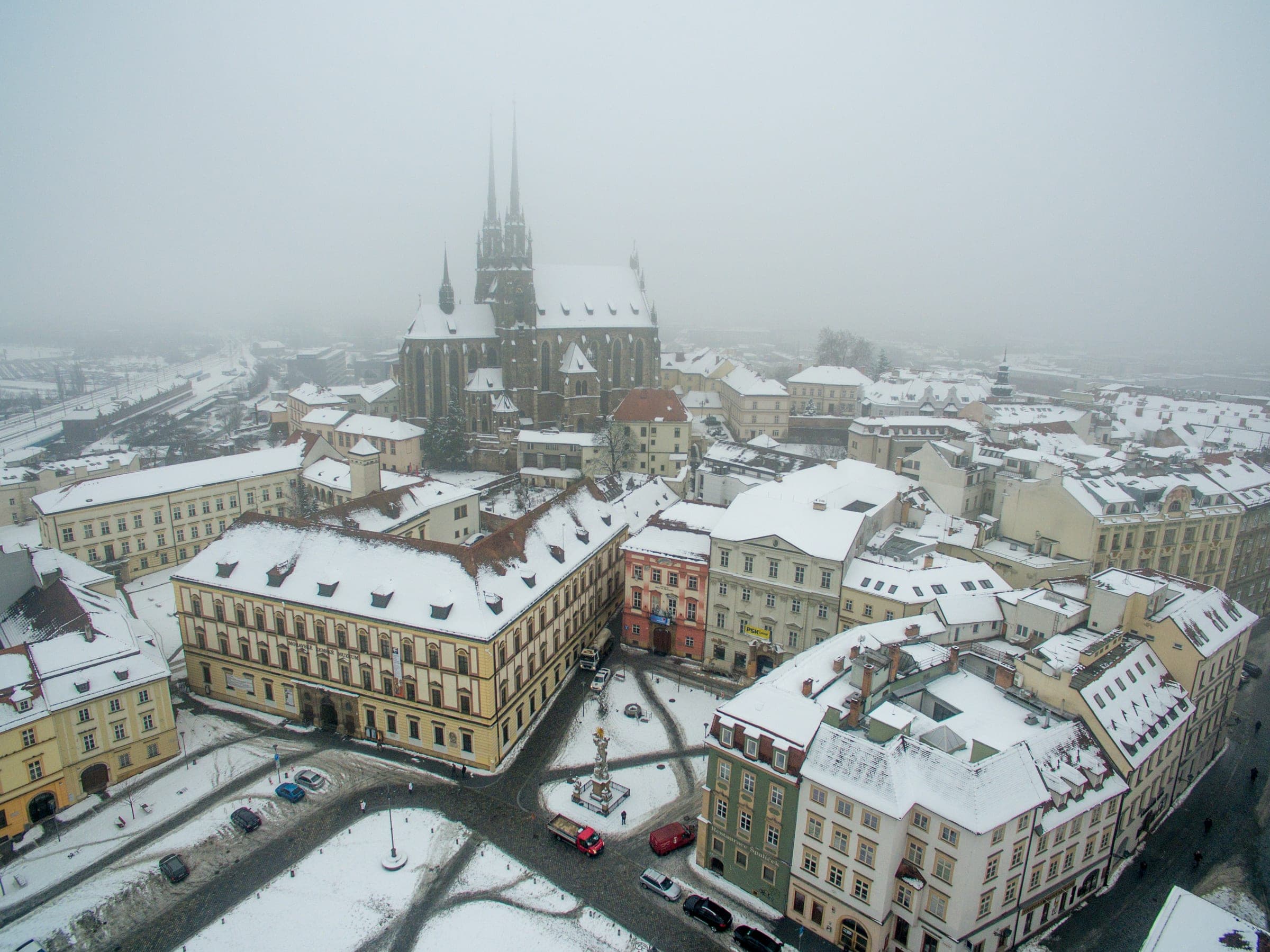 Snow covers Zelný trh and the roofs of Brno below the twin spires of the Cathedral of Saints Peter and Paul.