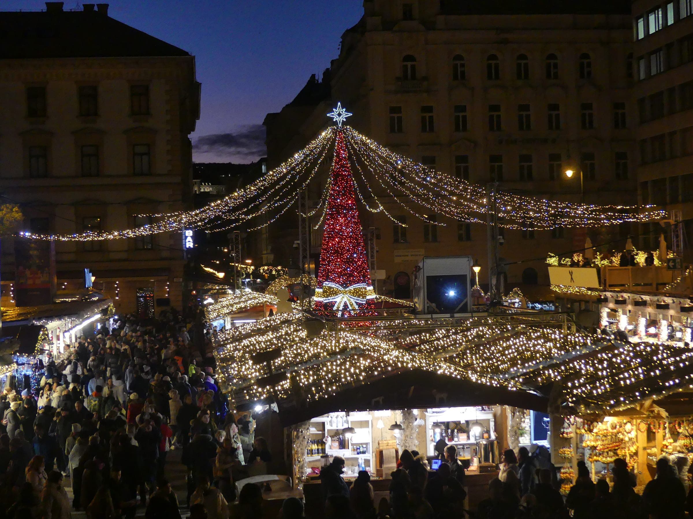 Strings of lights fan out from the red Christmas tree over the crowded stalls on Szent István tér at dusk.