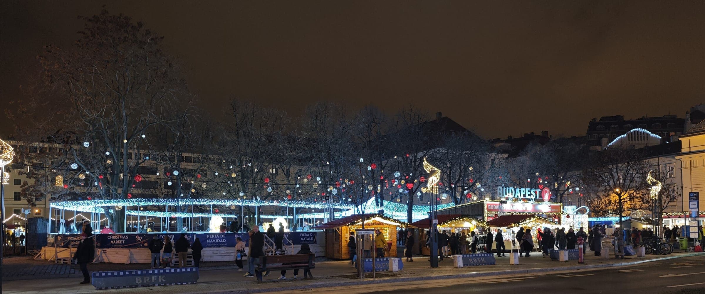 Lit trees and wooden stalls fill Városháza Park in Budapest on a night of the Christmas market.