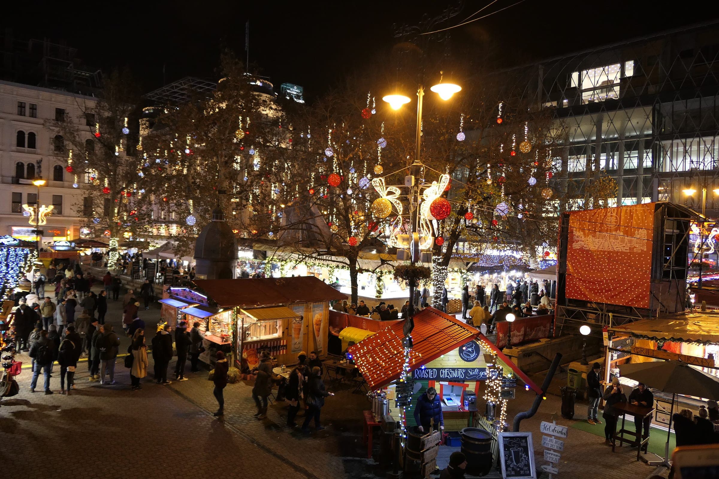 Lit stalls and decorated trees fill Vörösmarty tér in Budapest on a December night.