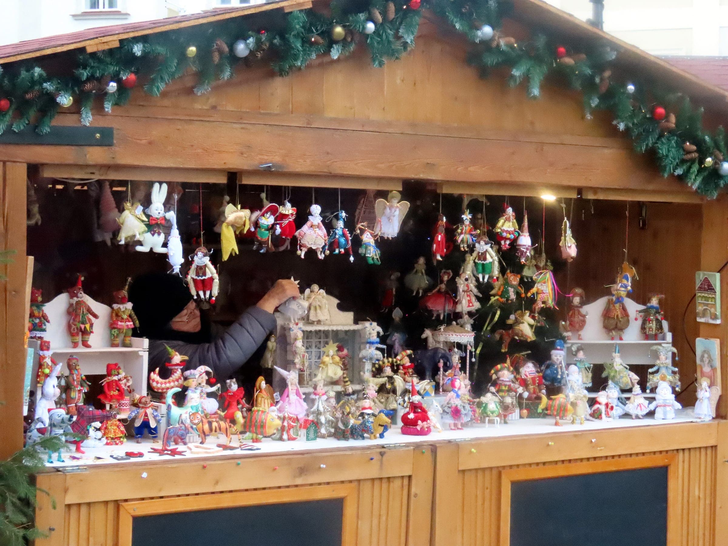 Painted puppets and hand-made ornaments hang in a garlanded stall at the Český Krumlov Christmas market.