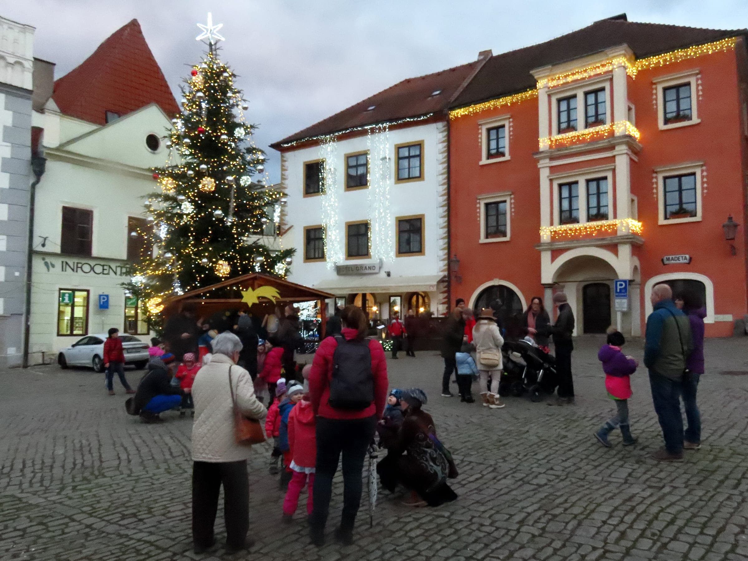 Lights come on along the gables of náměstí Svornosti in Český Krumlov as people gather by the Christmas tree.