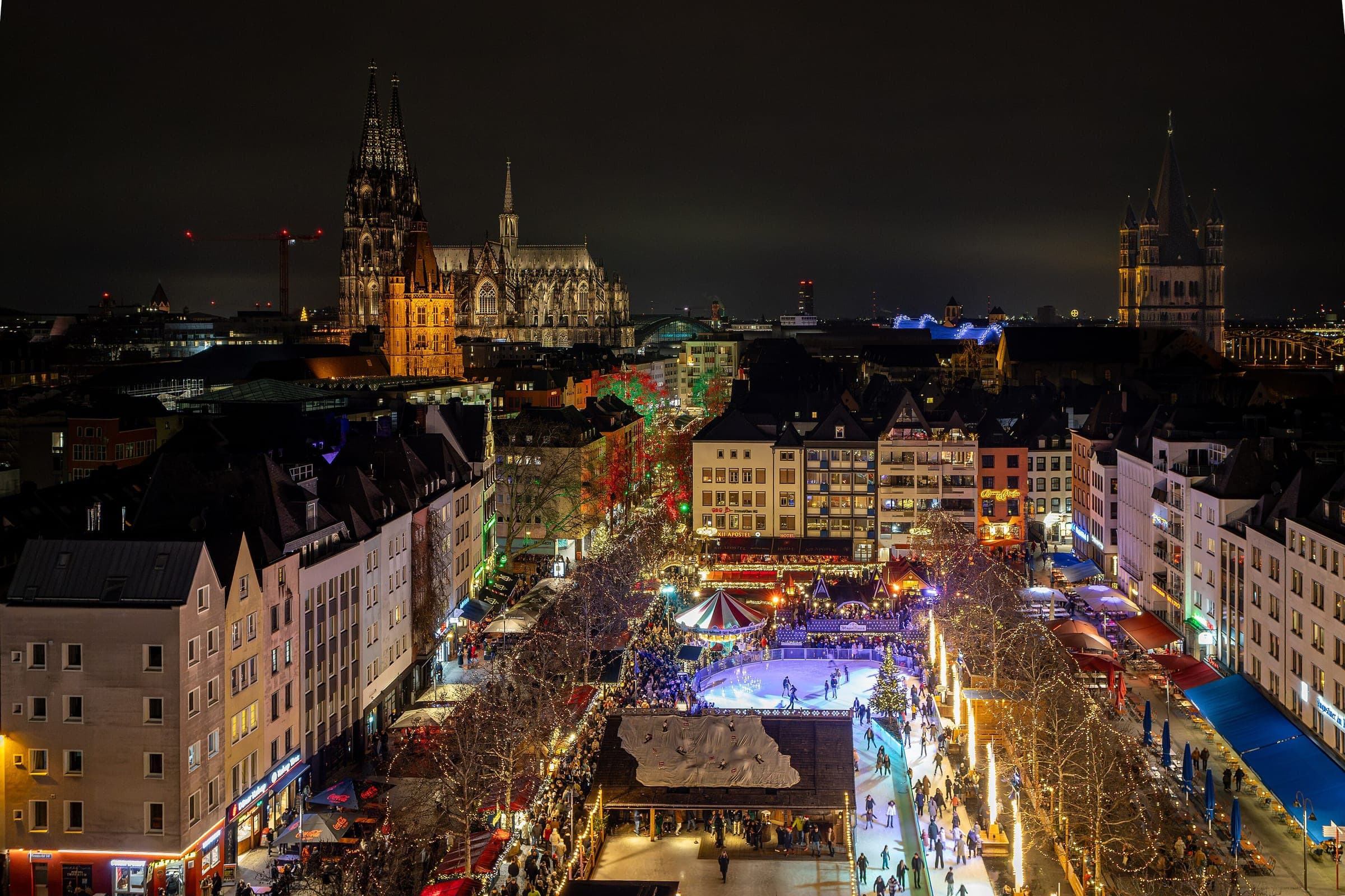 Heinzels Wintermärchen lights up the Heumarkt at night with Cologne Cathedral on the skyline behind