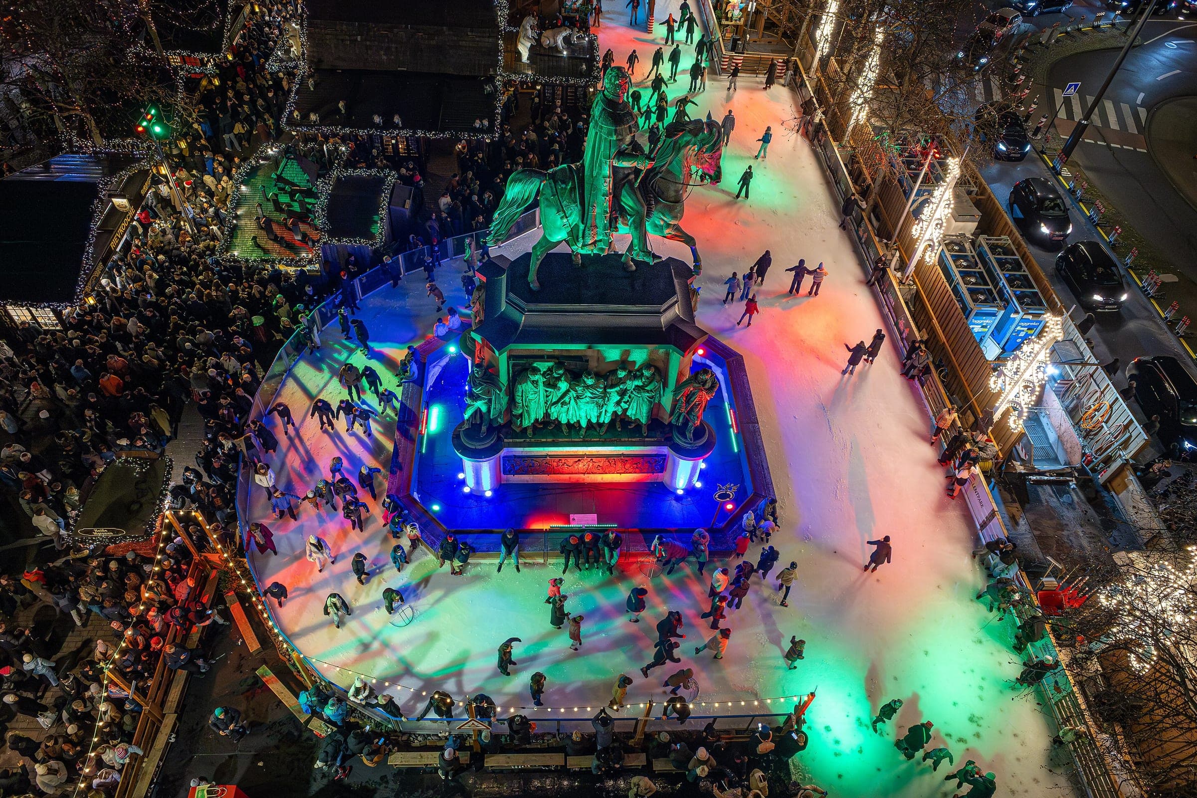 Skaters circle the lit ice rink around the equestrian statue on Cologne's Heumarkt