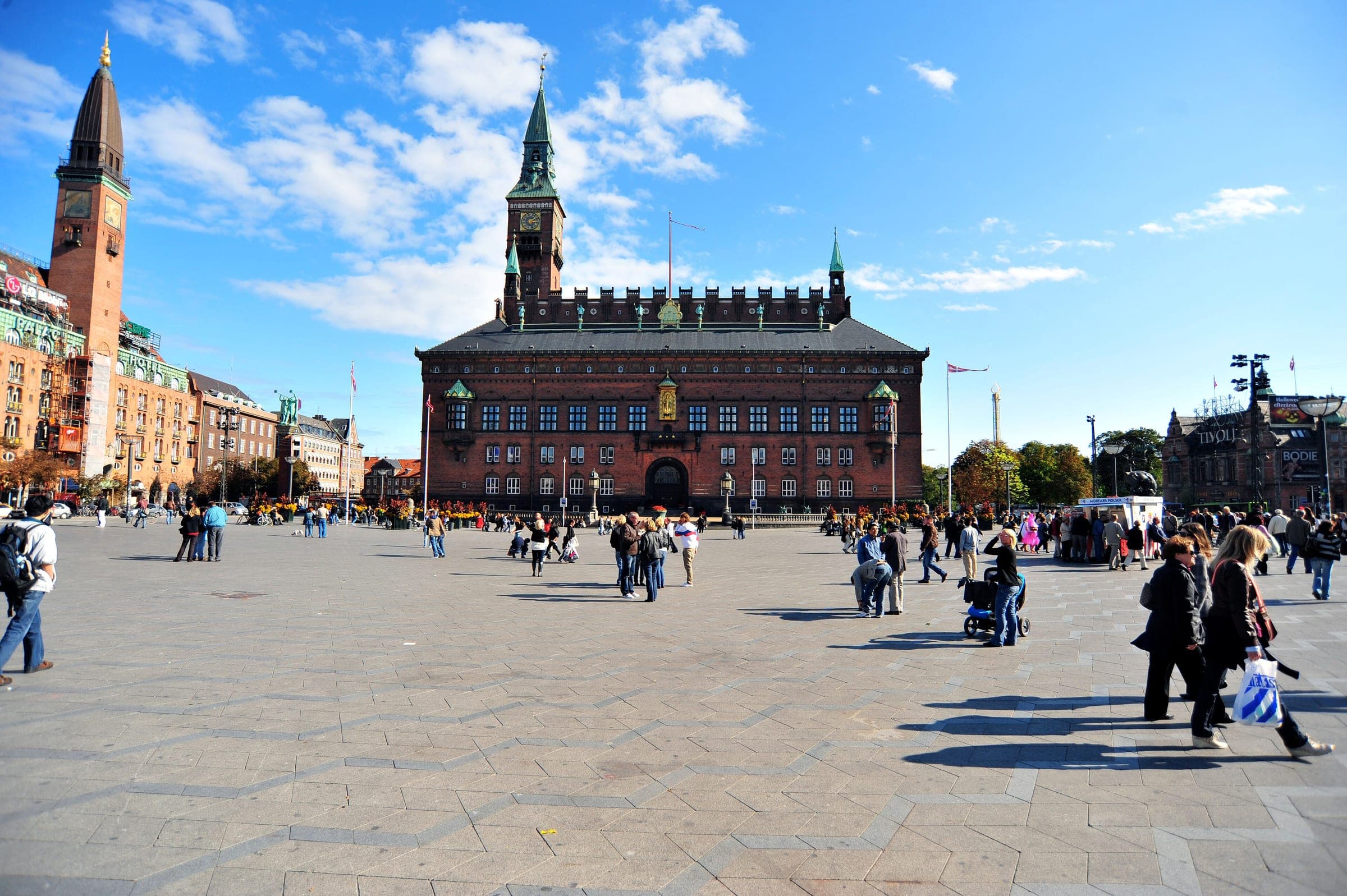 Copenhagen City Hall rises over the open paving of City Hall Square under a bright sky.