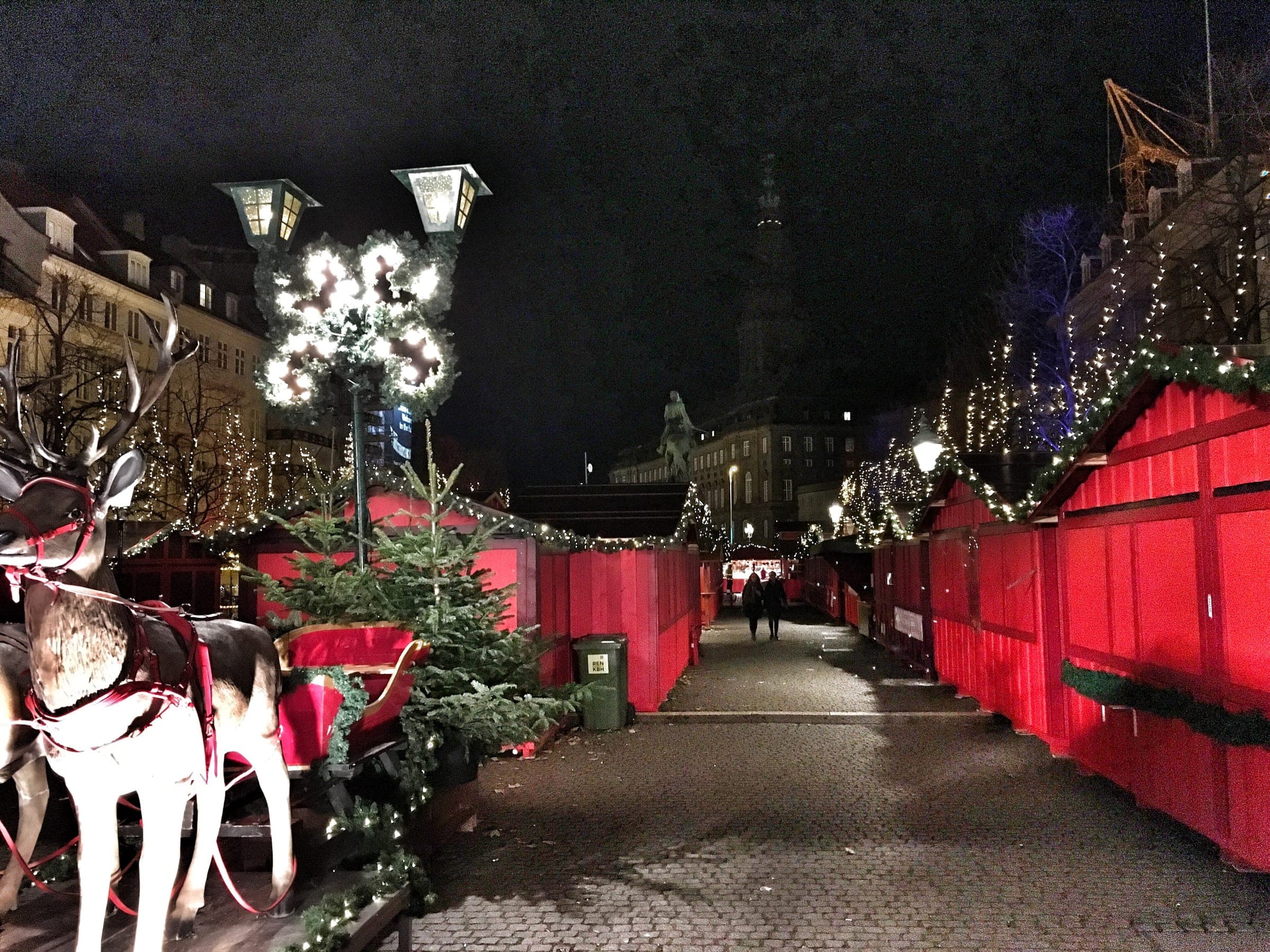 Red Christmas stalls hung with lights line the cobbles of Højbro Plads in Copenhagen at night.