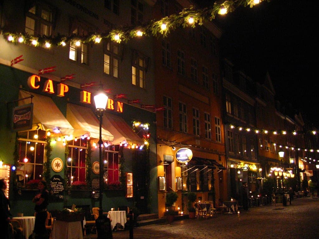 Christmas lights run along the restaurant fronts of the Nyhavn quay in Copenhagen at night.