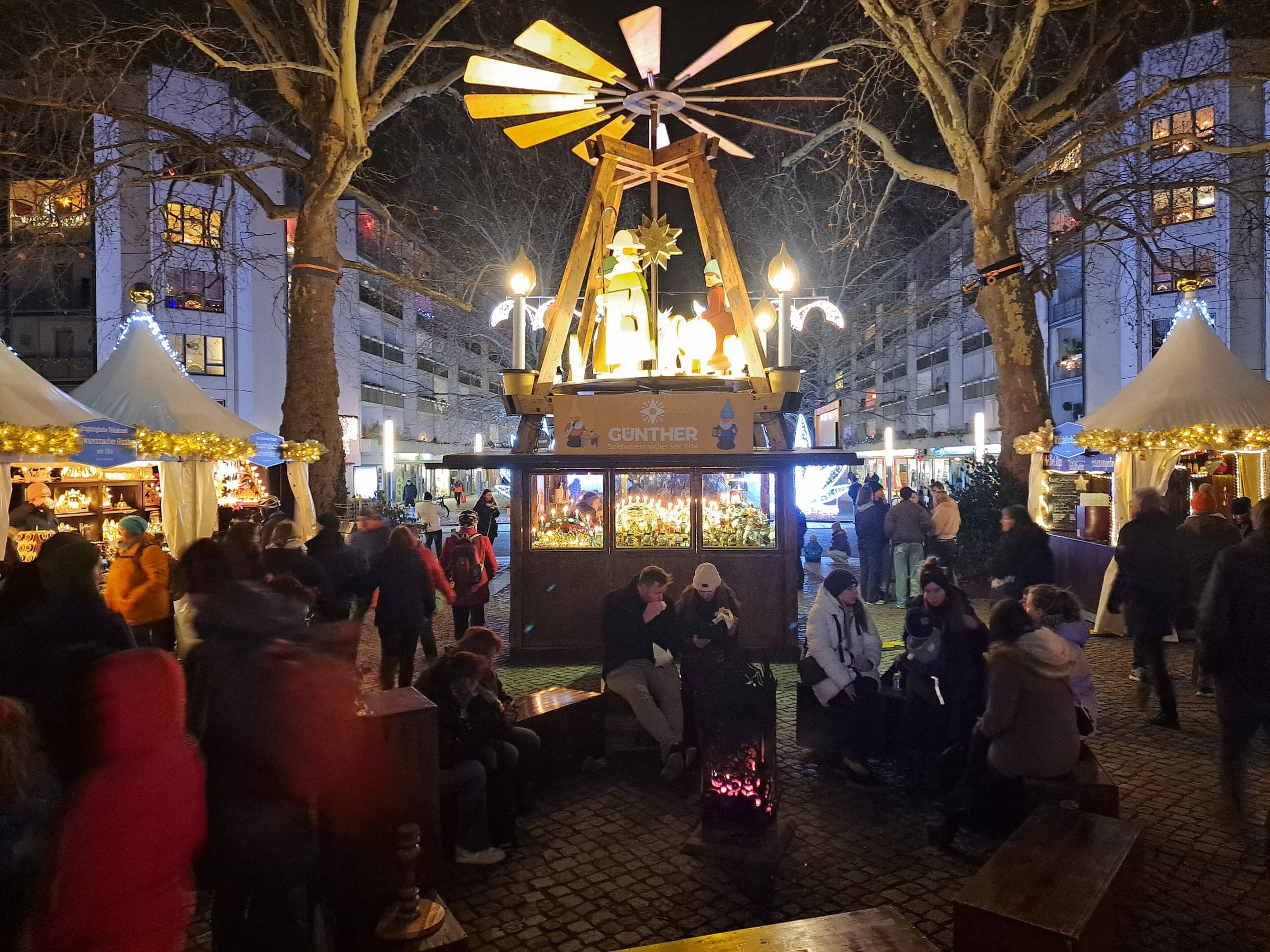 A Christmas pyramid turns above benches and stalls at the Augustusmarkt in Dresden's Neustadt at night.