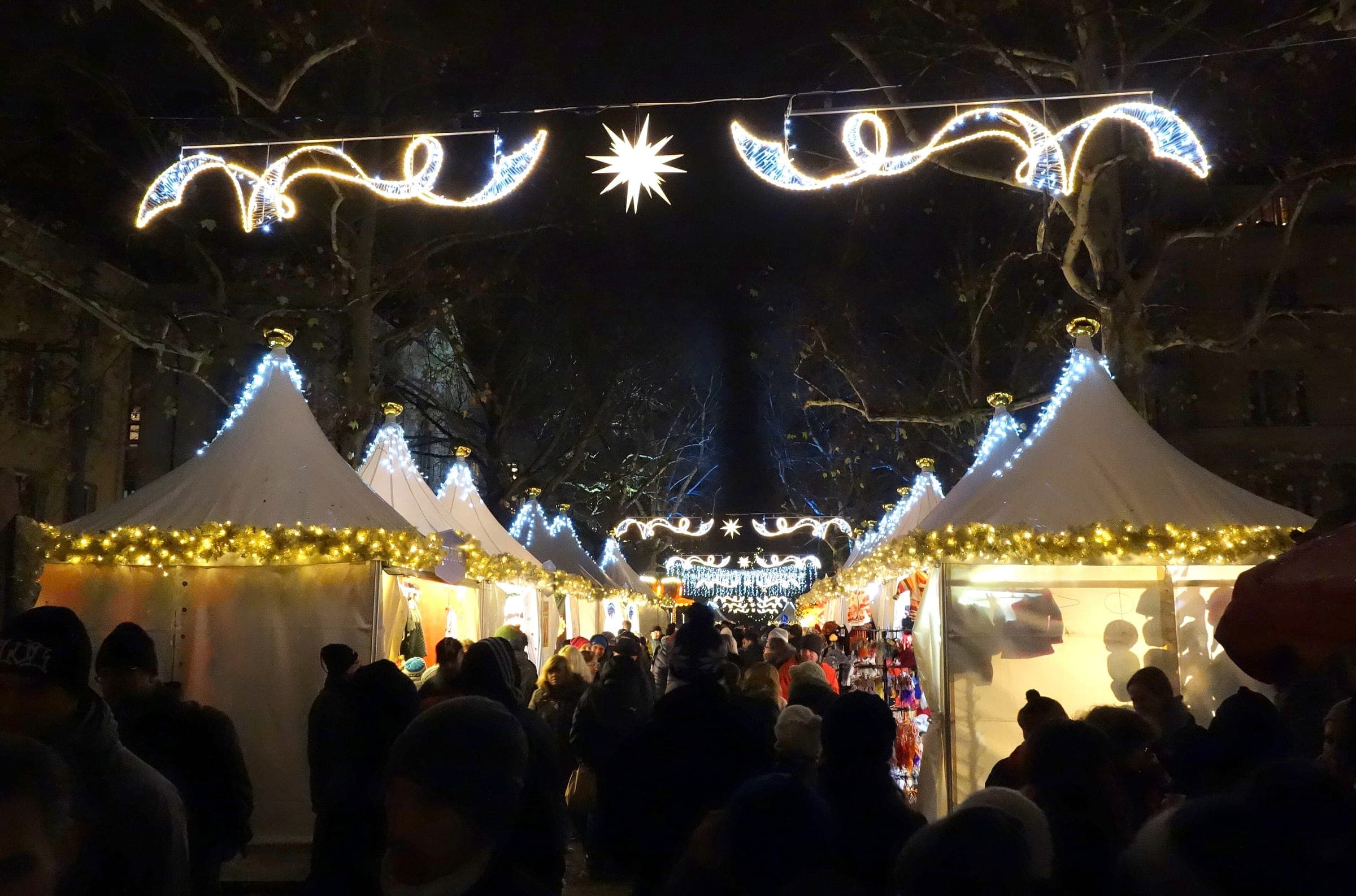 Light garlands hang over the white tents of the Augustusmarkt on Dresden's Hauptstraße at night.
