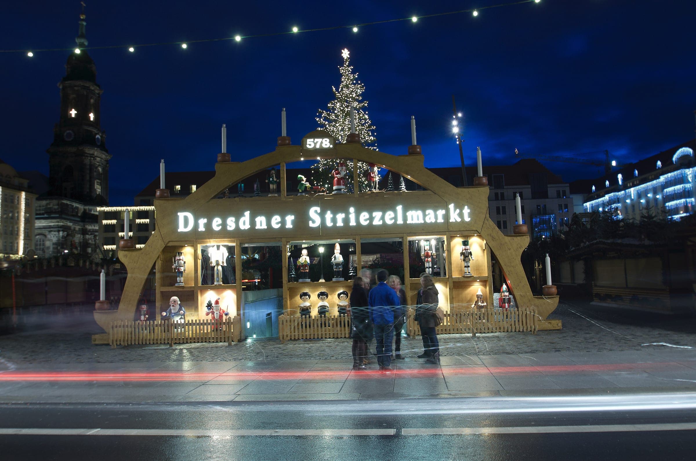 The Striezelmarkt's candle arch glows at blue hour below the Kreuzkirche tower in Dresden.