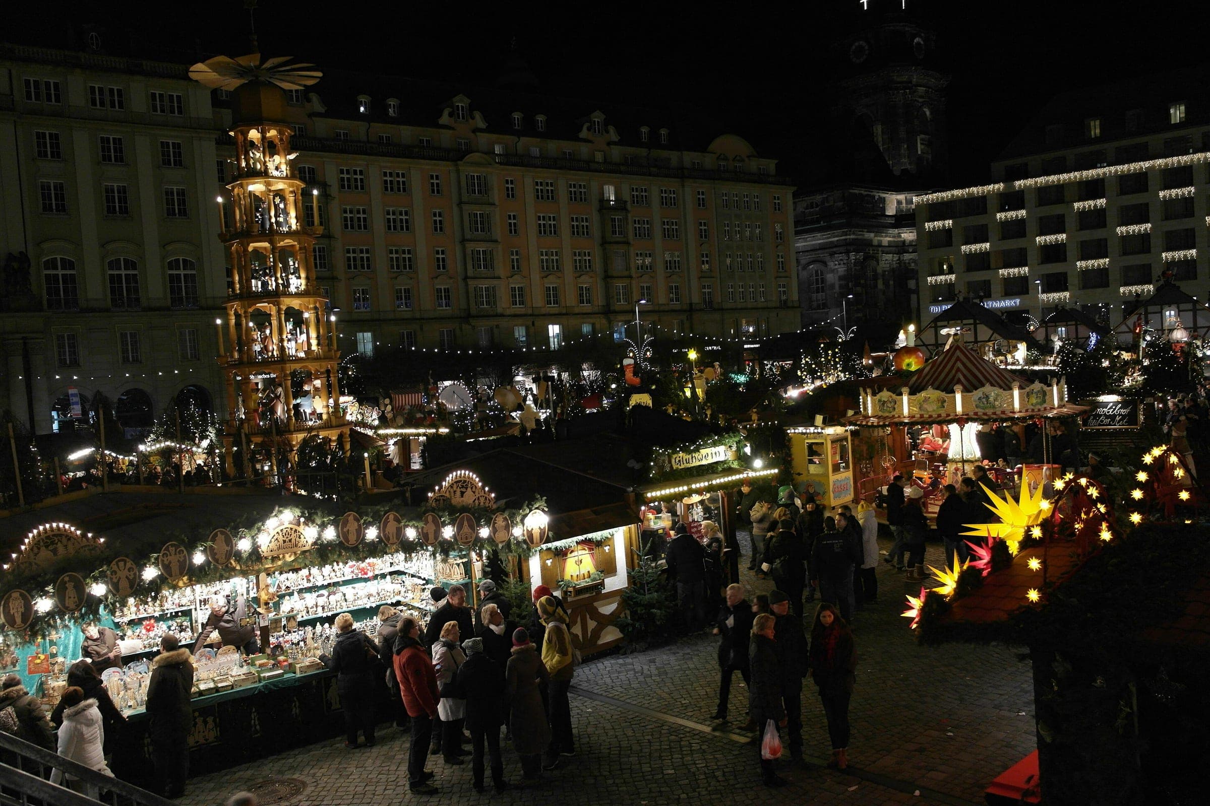 The giant wooden pyramid towers over lit stalls at the Striezelmarkt on Dresden's Altmarkt at night.