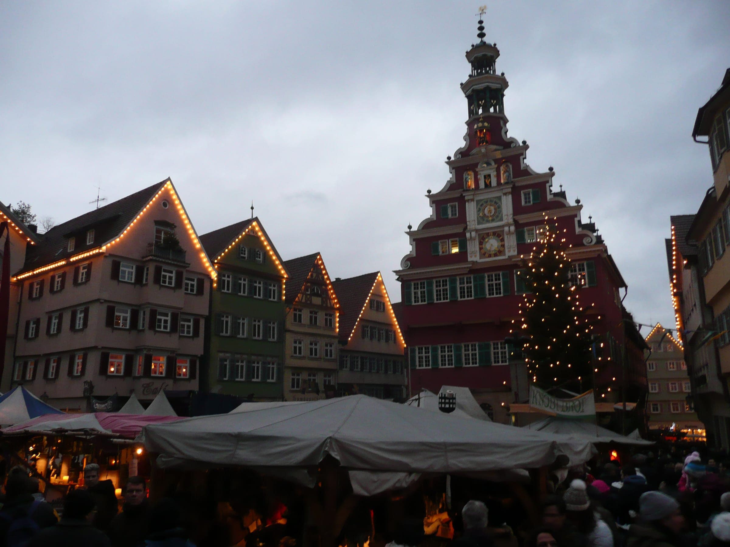 Lit gables and a Christmas tree frame the Altes Rathaus above the market tents in Esslingen at dusk.
