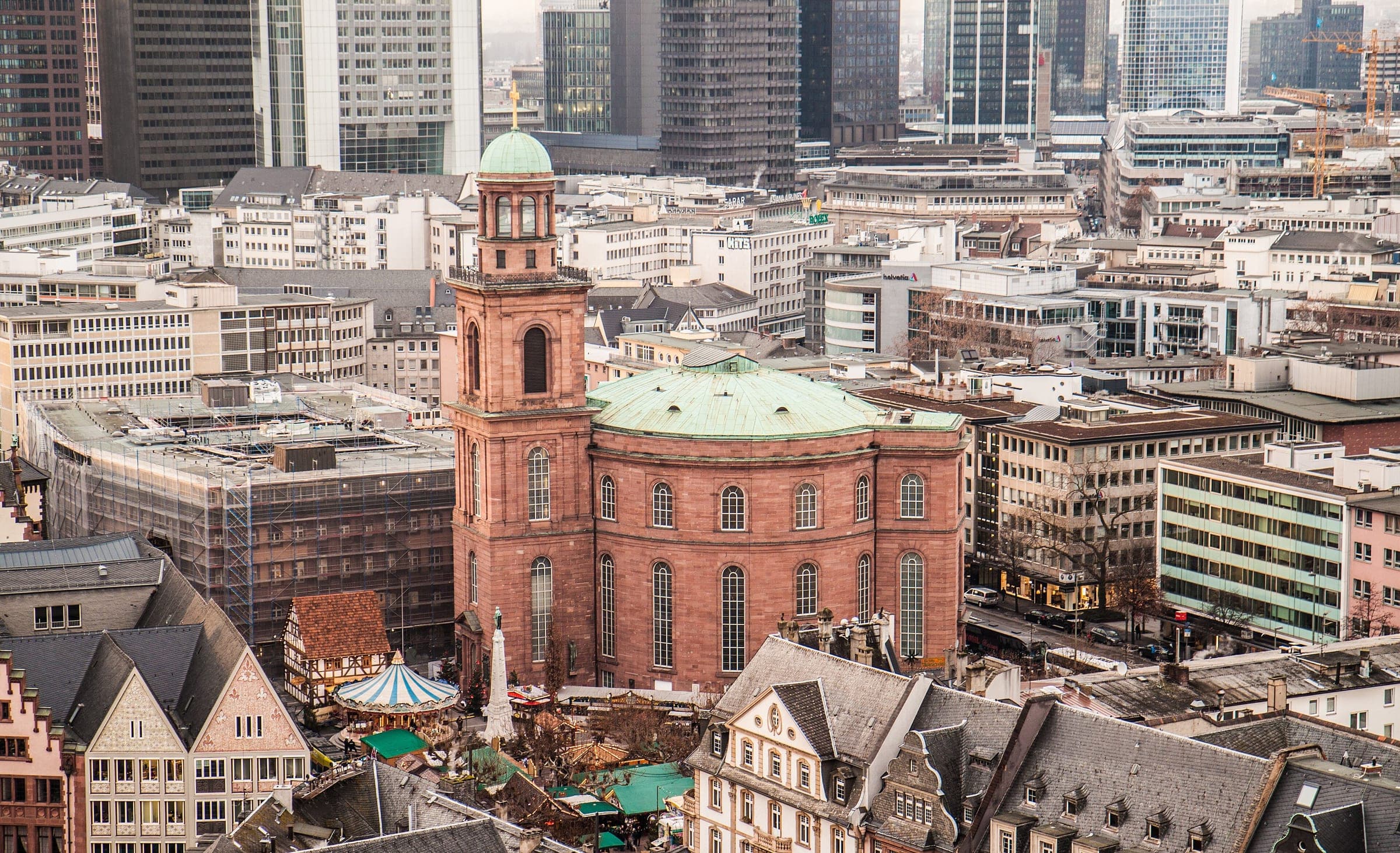 The round Paulskirche rises above the Christmas market roofs in Frankfurt, seen from the cathedral tower.