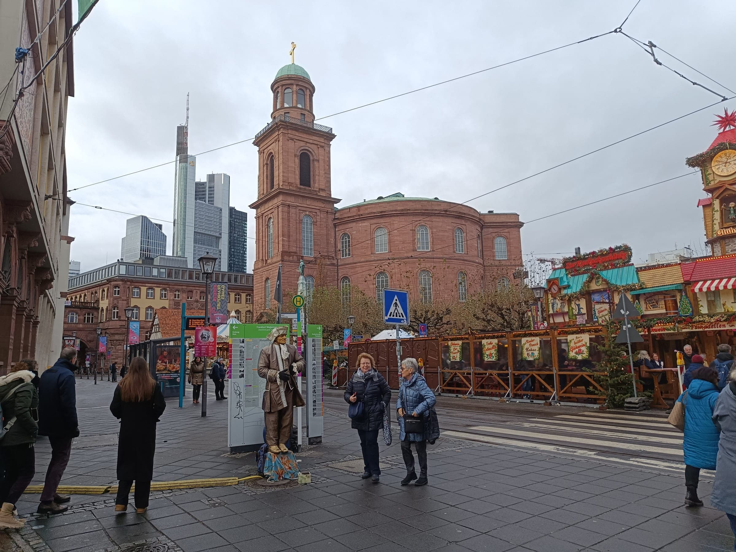 Market stalls stand on Paulsplatz in Frankfurt before the Paulskirche and the towers of the banking district.