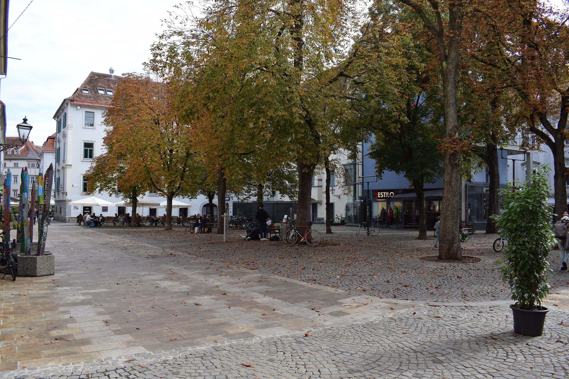 Benches and bicycles wait under the chestnut trees of Färberplatz in the old town of Graz.