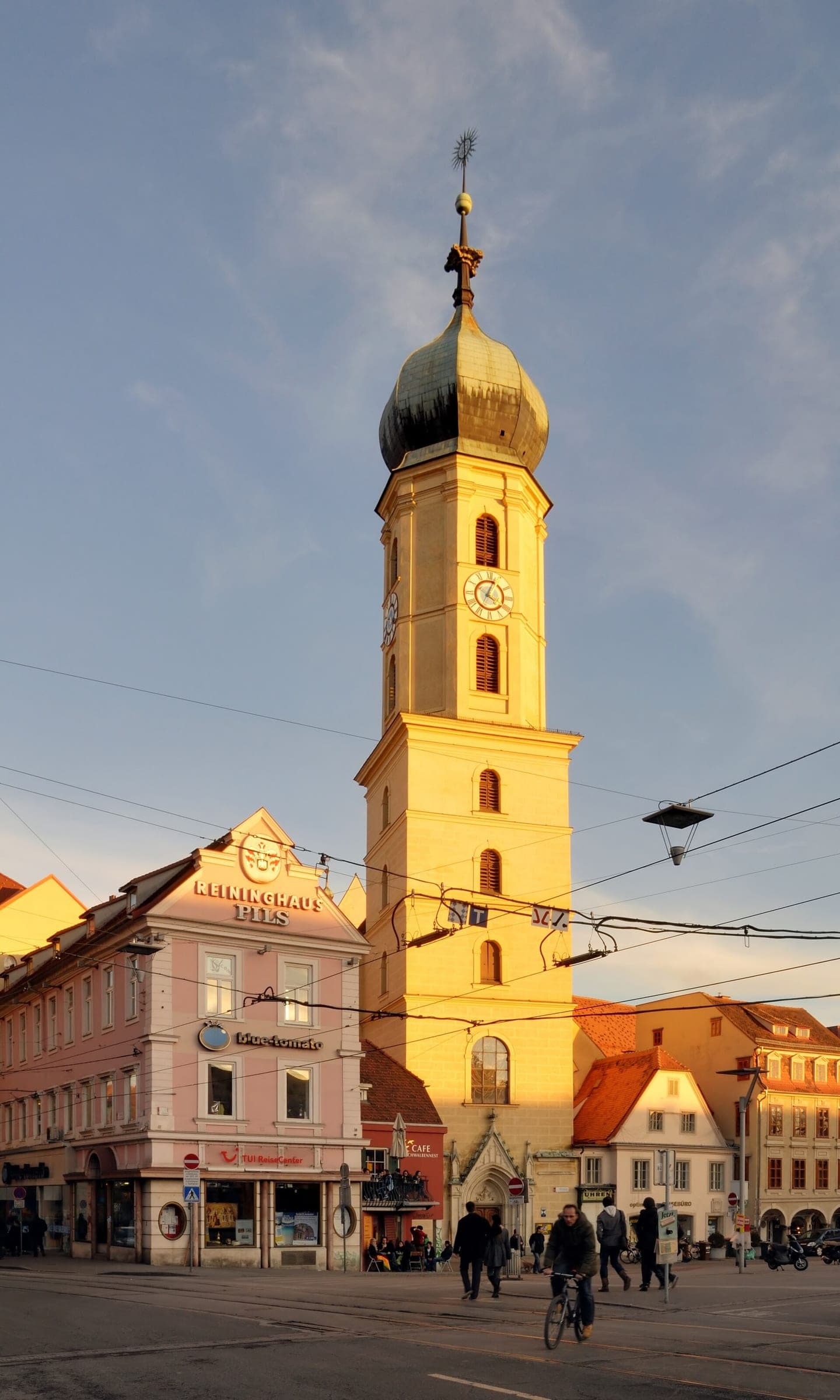 Low January sun turns the onion-domed tower of the Franziskanerkirche gold above the Graz old town.