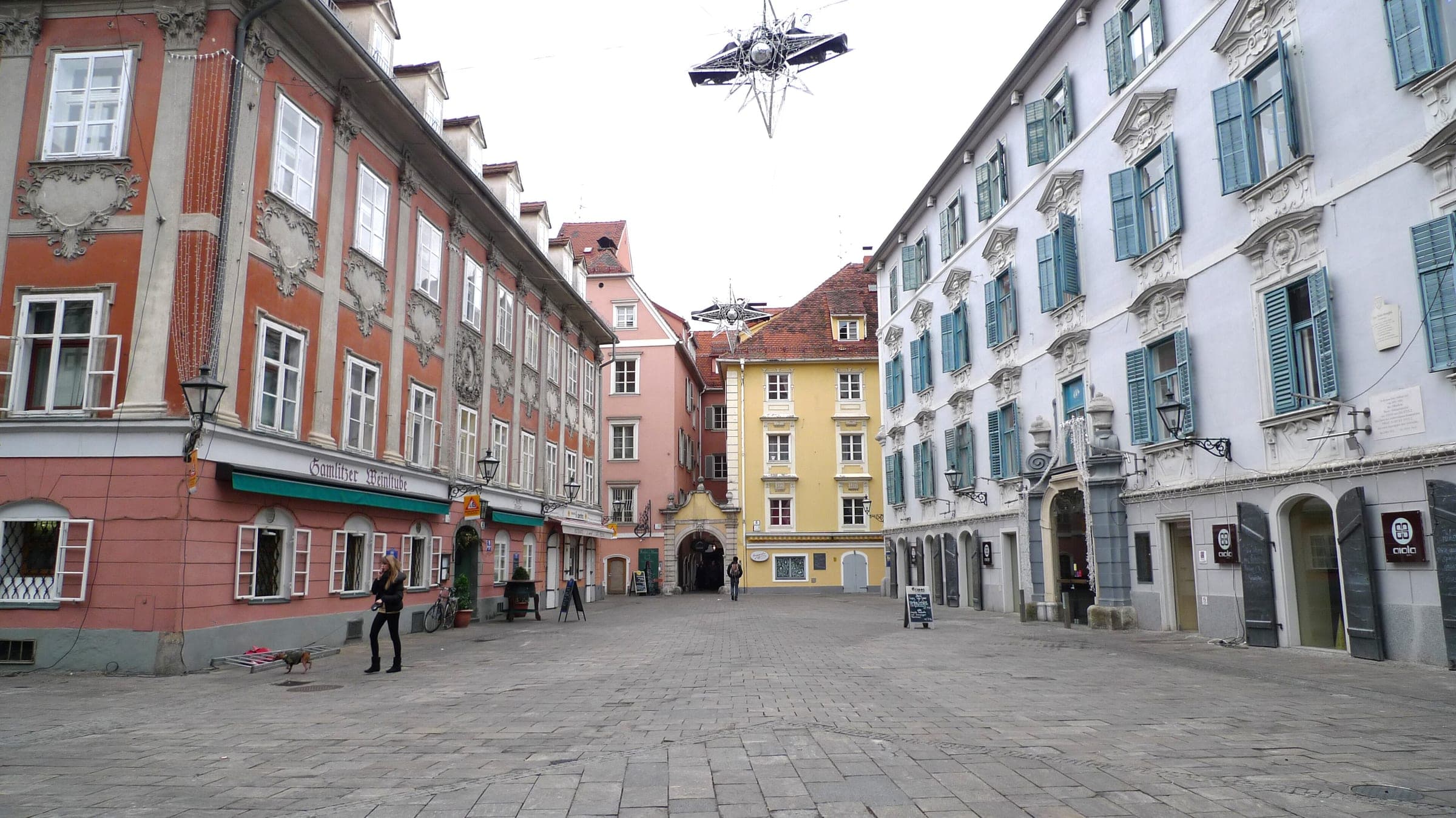 A hanging star lamp floats over the Mehlplatz in Graz between Palais Inzaghi and the rose-red Bürgerhaus.