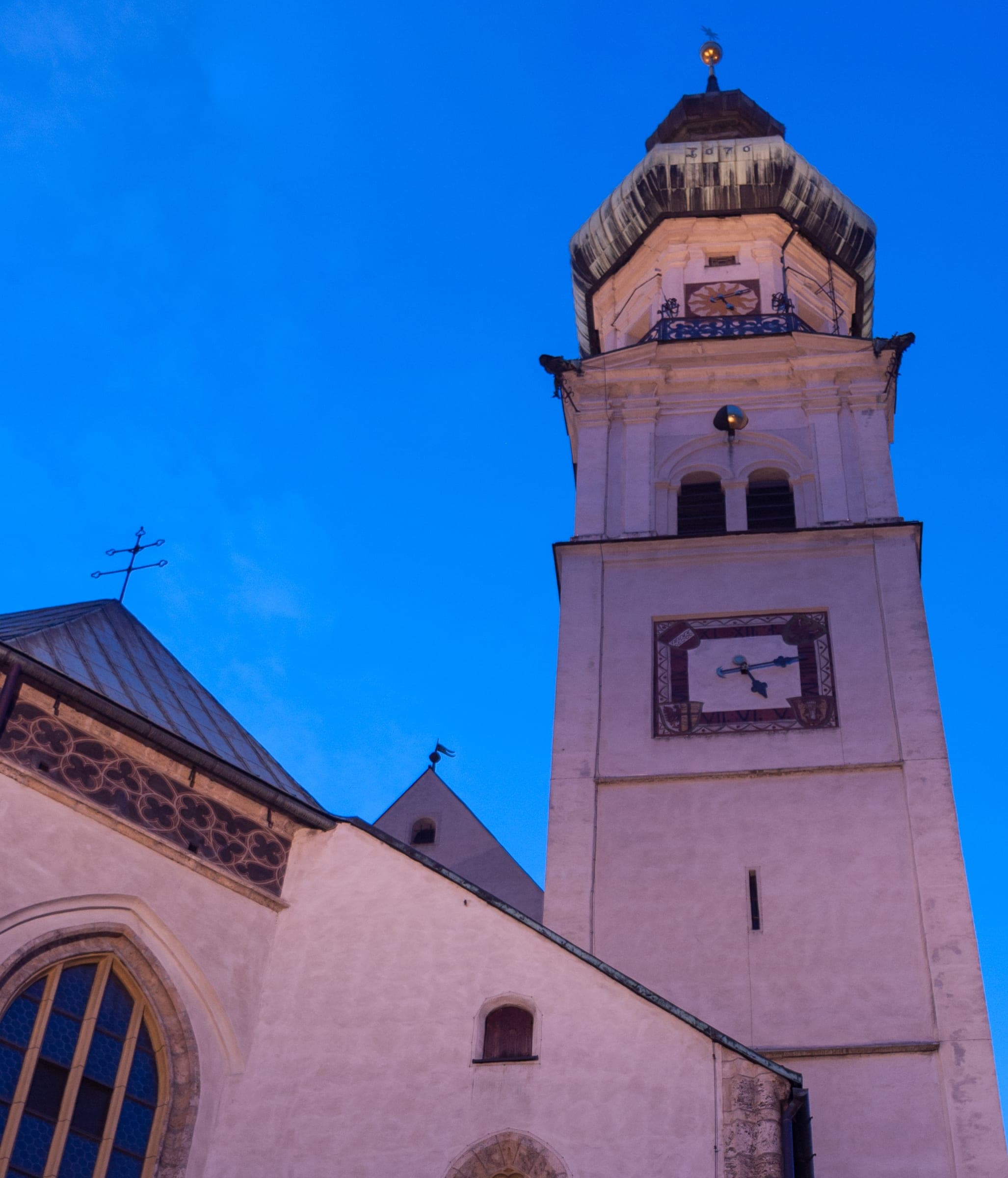 The tower of St. Nikolaus parish church in Hall in Tirol stands pale against a deep blue January sky.