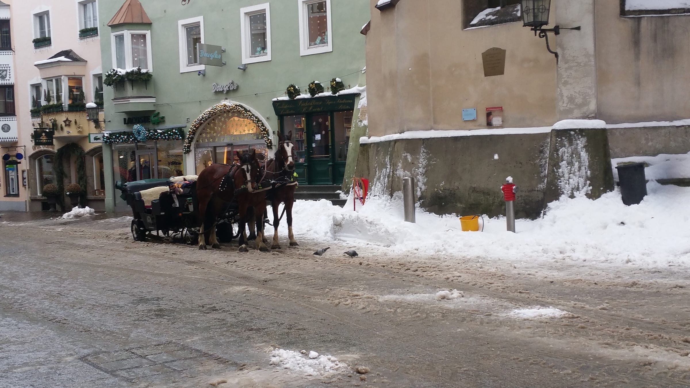 A horse-drawn carriage waits on a snowy corner of Kitzbühel's old town in January.