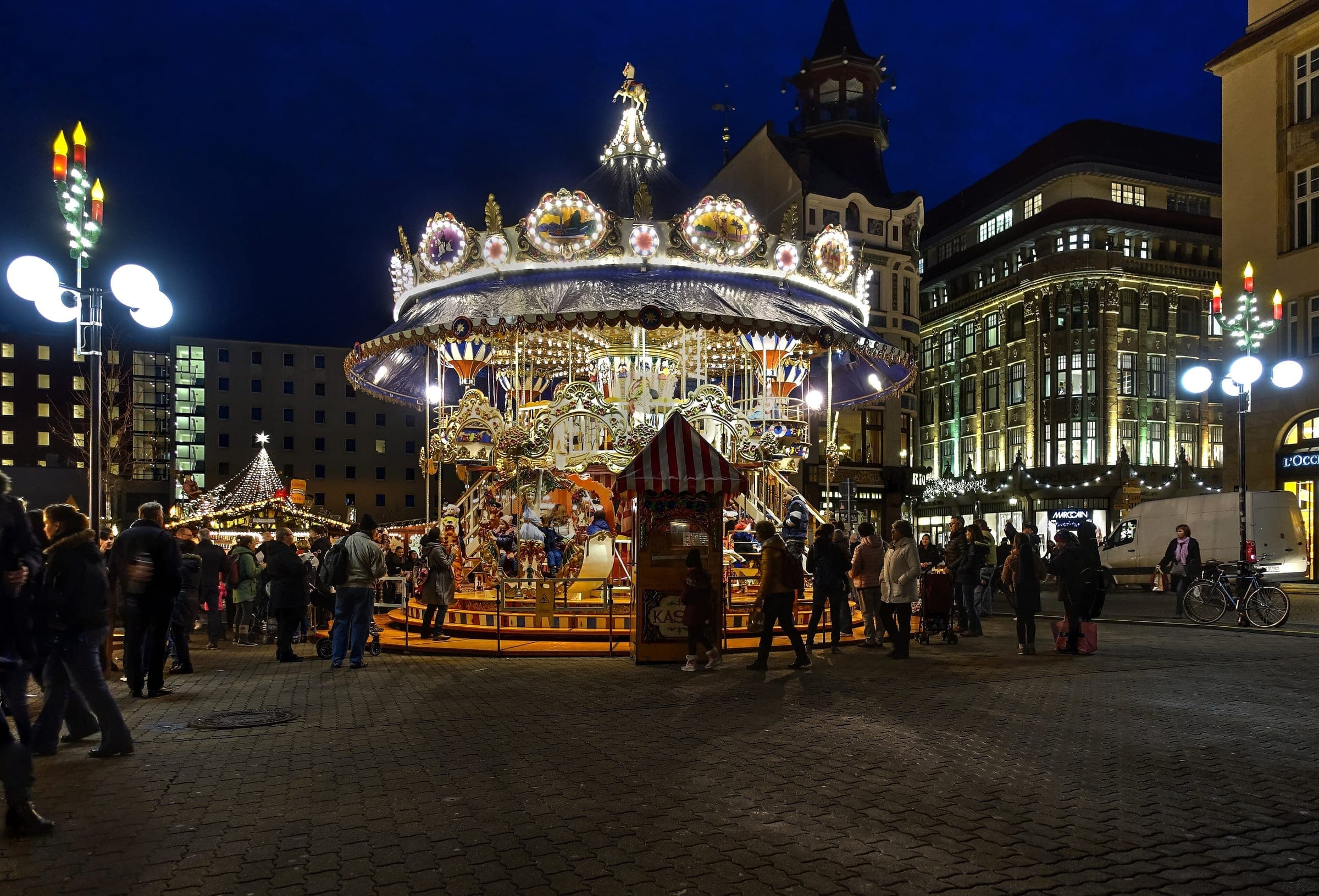 A two-tier carousel glows on the Reichsstraße during the Leipzig Christmas market at night.