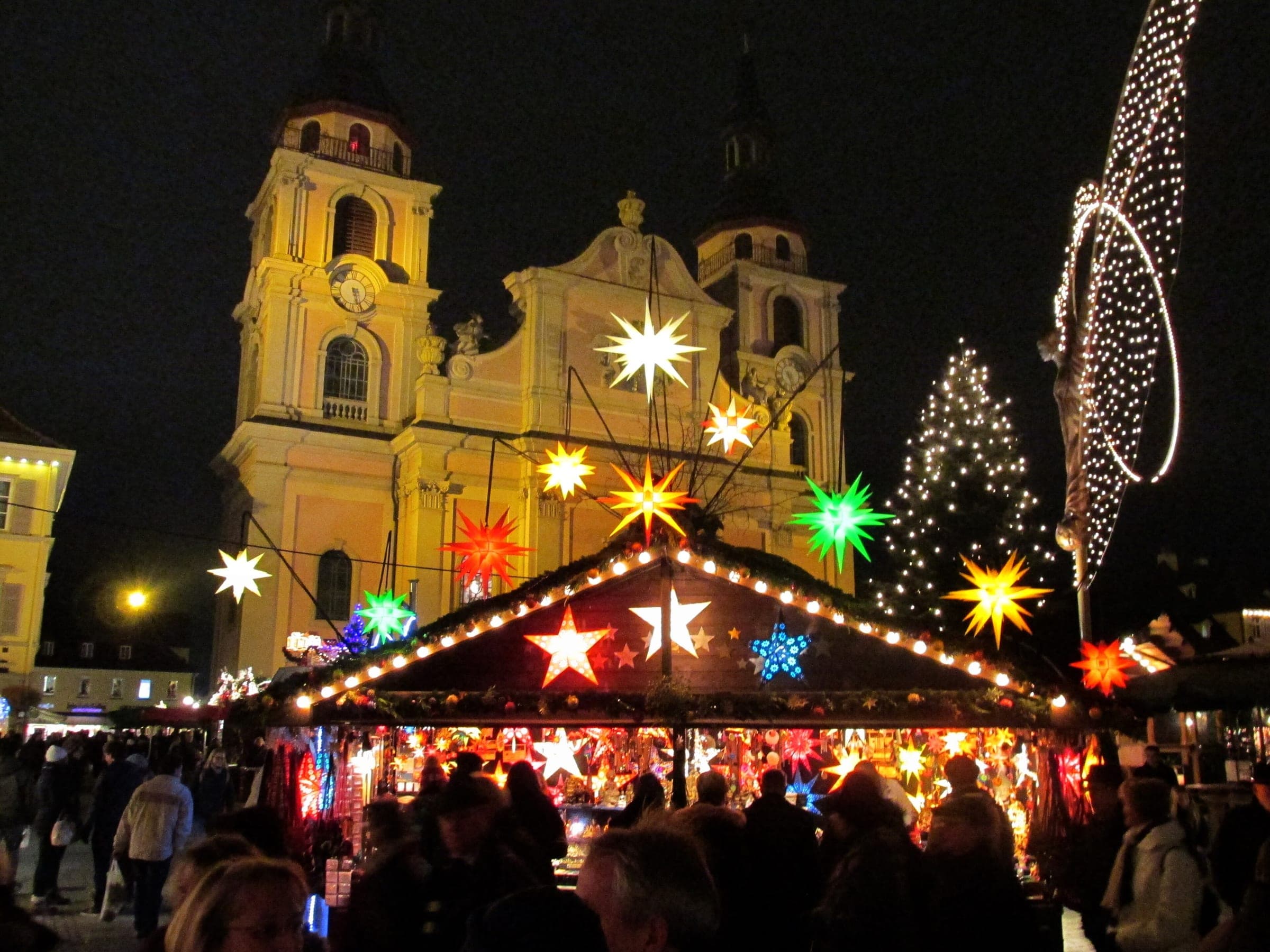 Coloured paper stars glow on a stall roof below the Stadtkirche at the Ludwigsburg Christmas market.